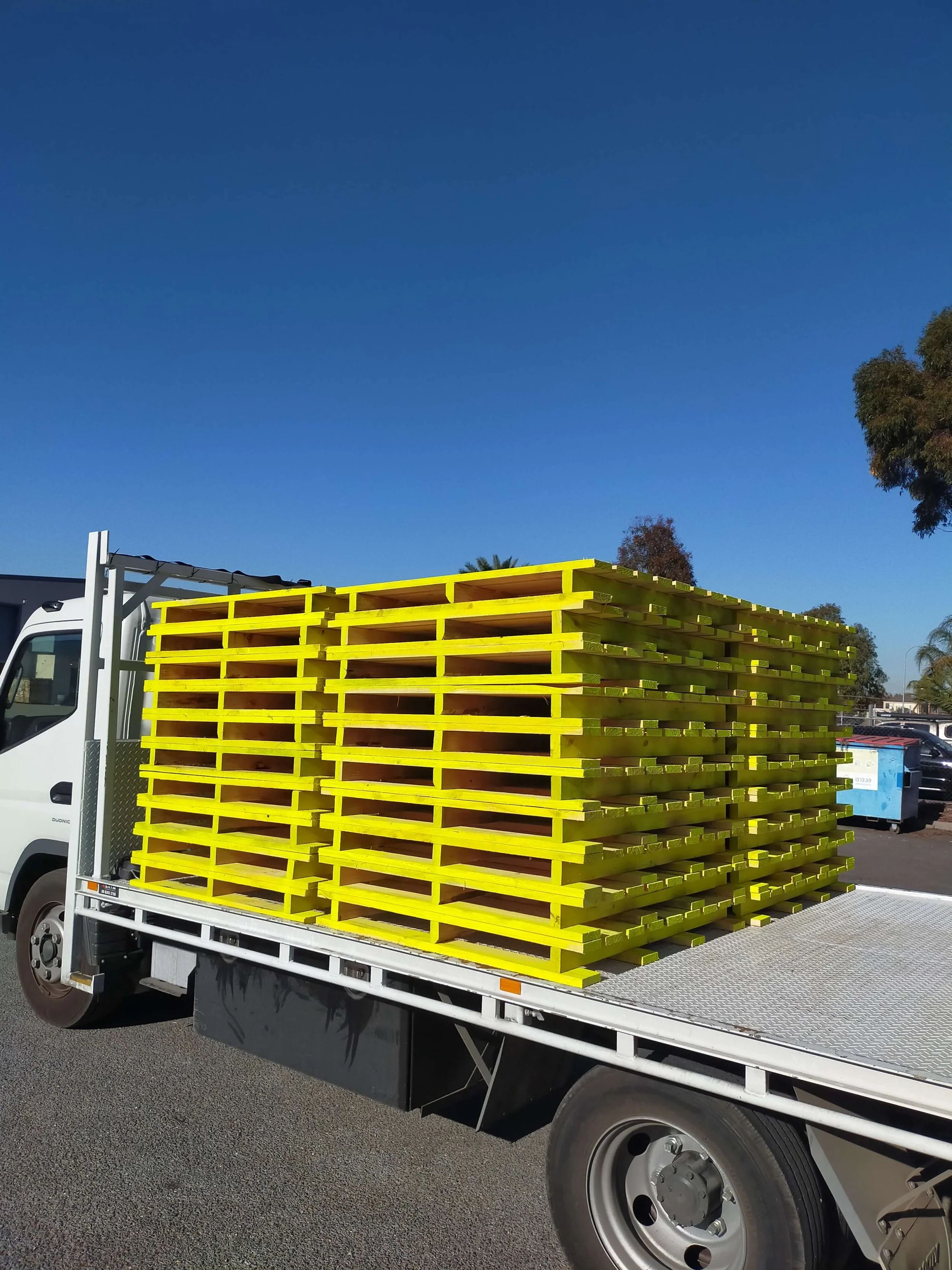Stack of yellow wooden pallets on a flatbed truck.