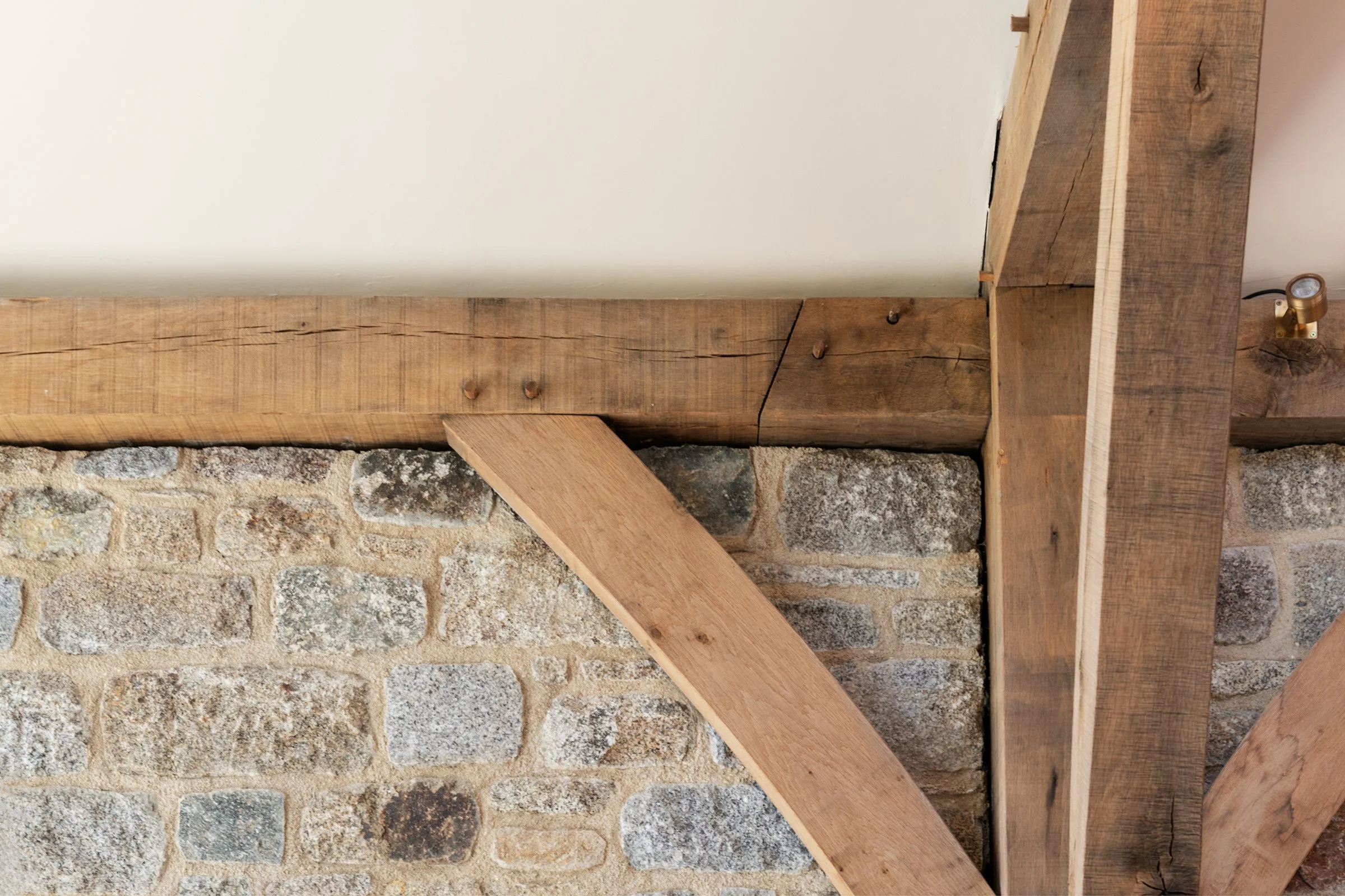 Close-up of wooden framing on a stone wall with a small light fixture attached.
