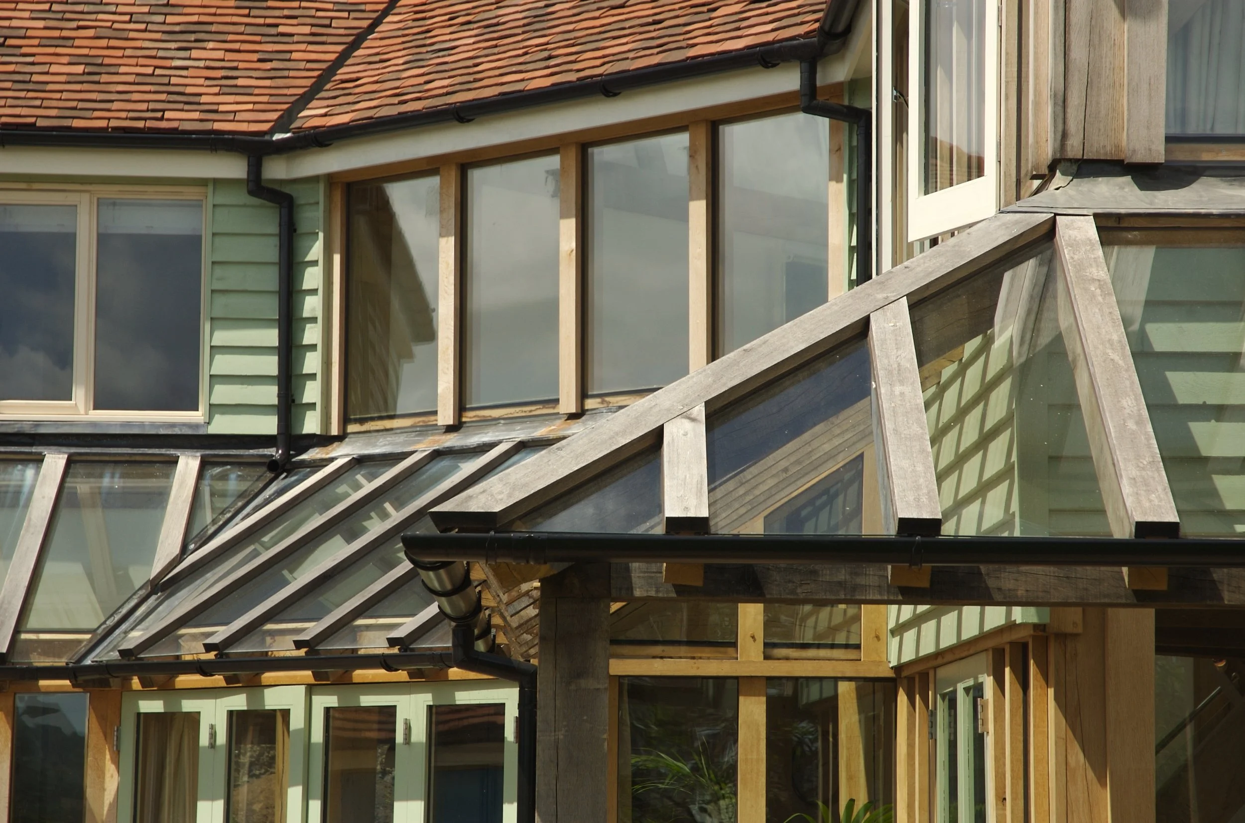 Close-up of a house under construction, showing window frames, wooden beams, and a glass roof section.
