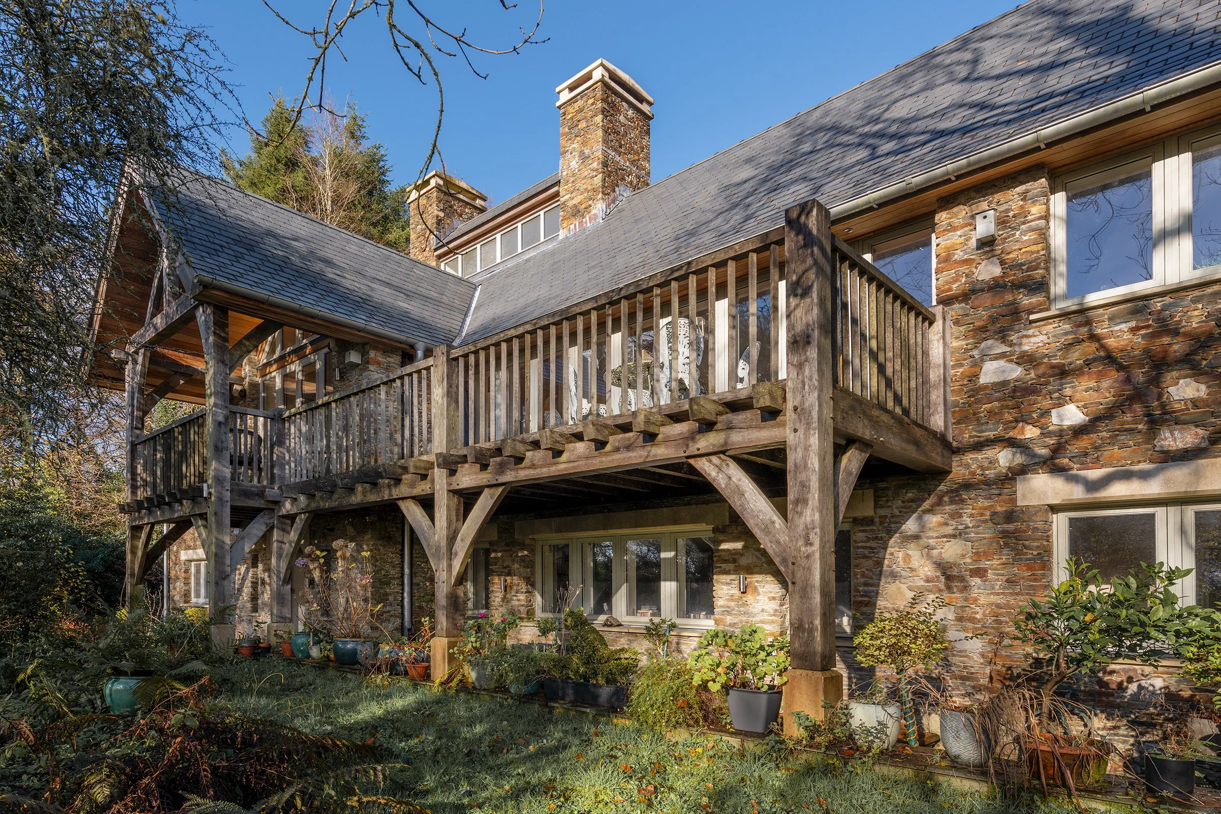 Large stone house with a slate roof and a projecting gable with an oak framed balcony.