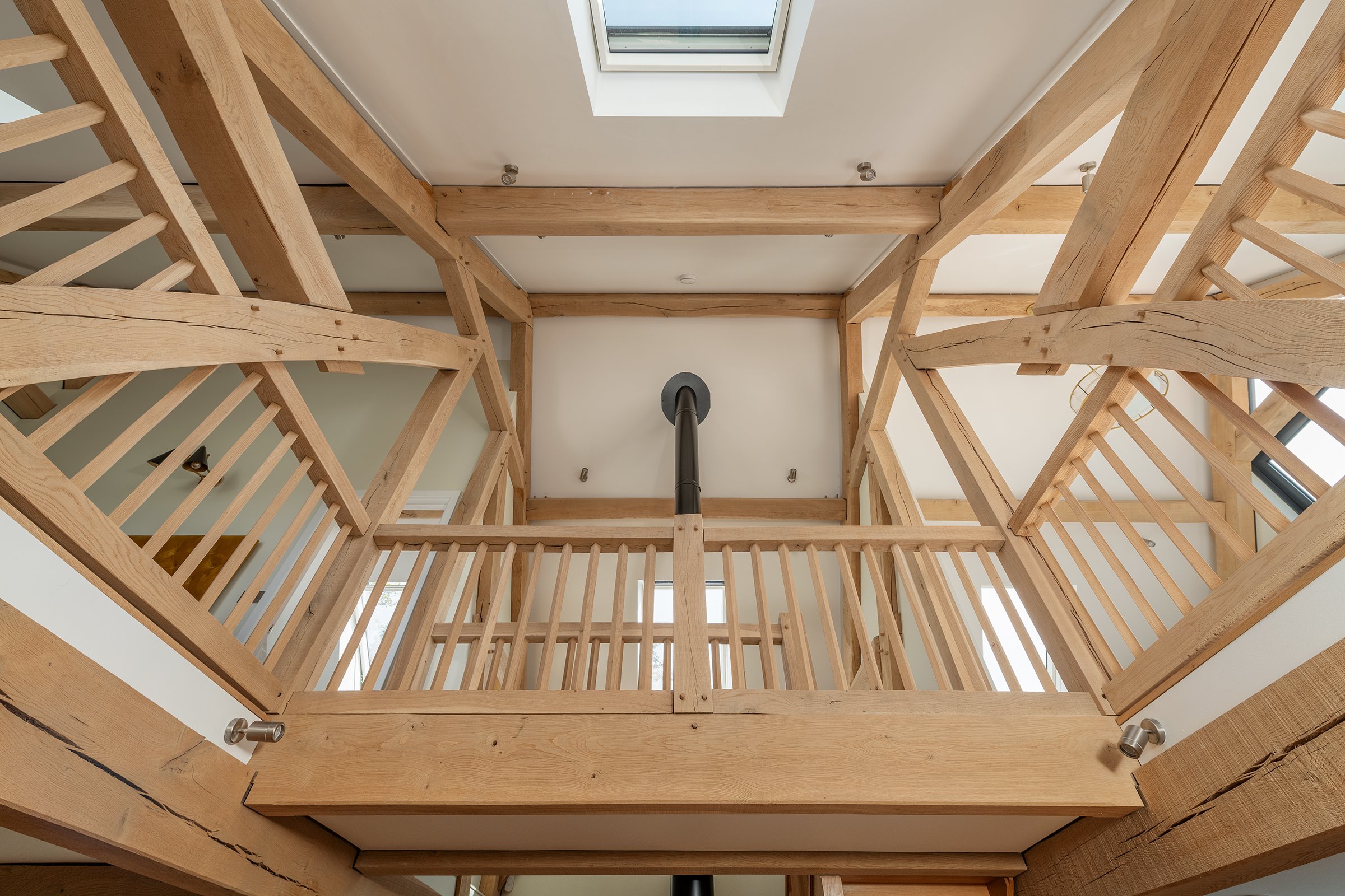 View looking up at wooden stair railing and ceiling with skylight in a modern home.