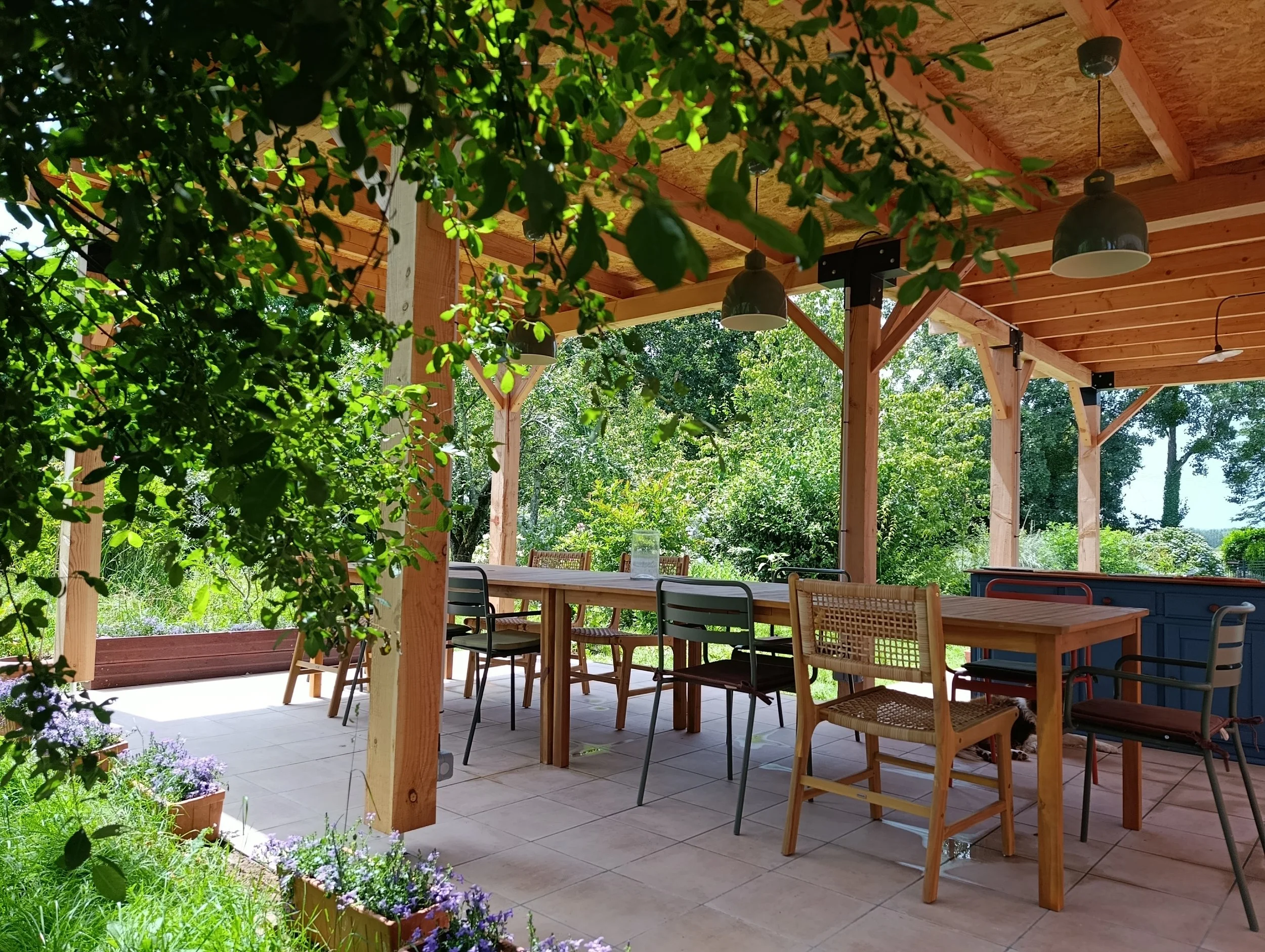 buitenterras met zithoek en koffiehoek en bar ontbijtruimte in een tuin vol bloemen en fruitbomen