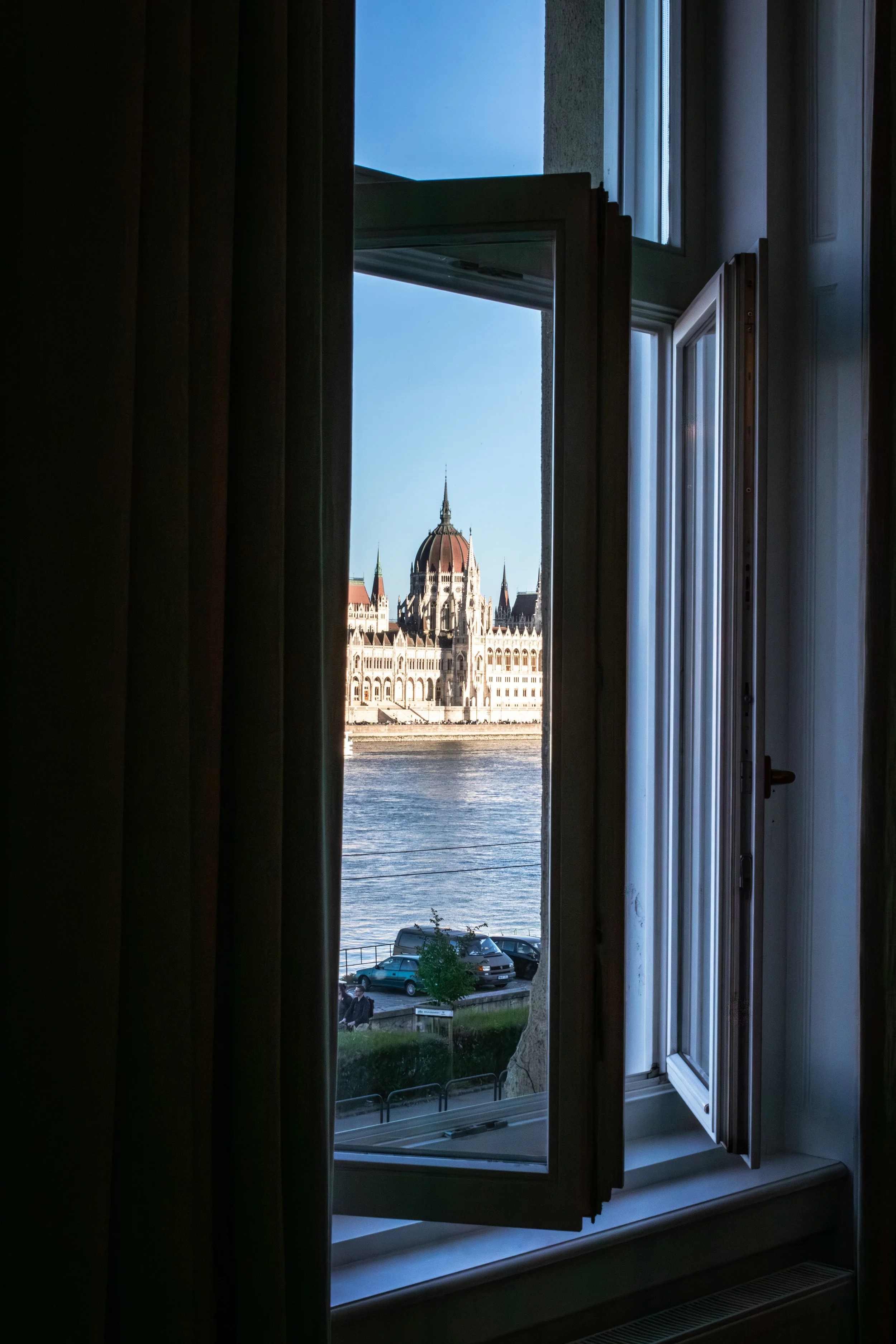 A cityscape featuring the Hungarian Parliament building and the Chain Bridge over the Danube River in Budapest, Hungary, during sunset.