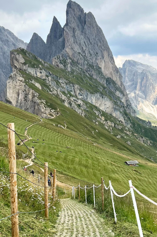 Trail leading to Seceda ridgeline with hikers and Odle mountains above Val Gardena.