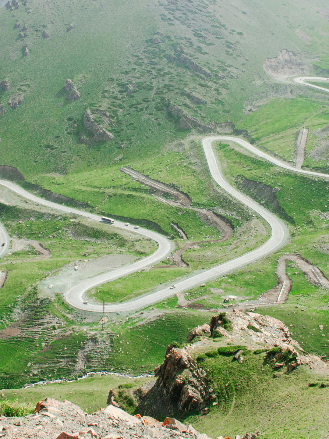 Winding mountain road through green hills in the Dolomites