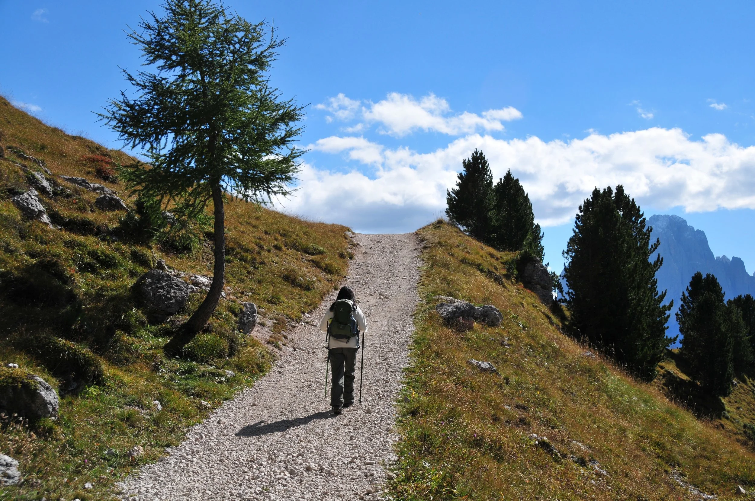 Hiker walking uphill on a Dolomites trail
