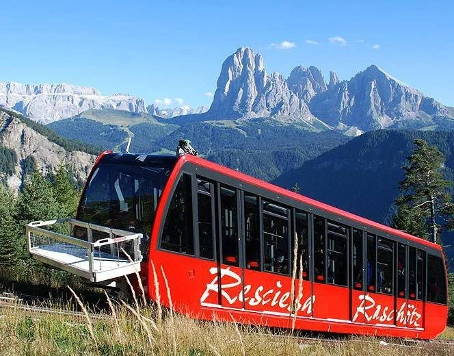 funicular going up a mountain with dolomites in background