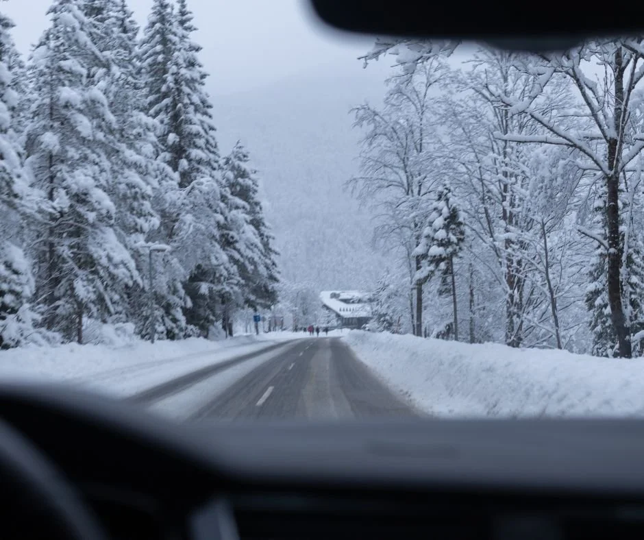 “Mountain road in winter with snow on the sides and foggy skies.