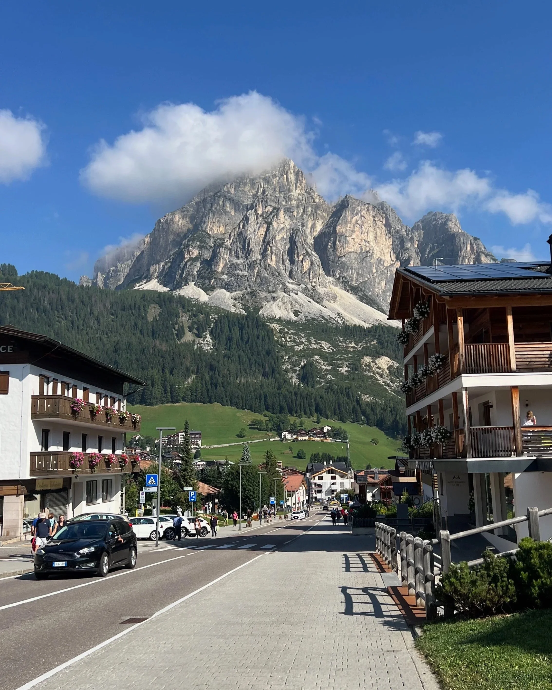 Road through a Dolomites village below the mountains in Corvara