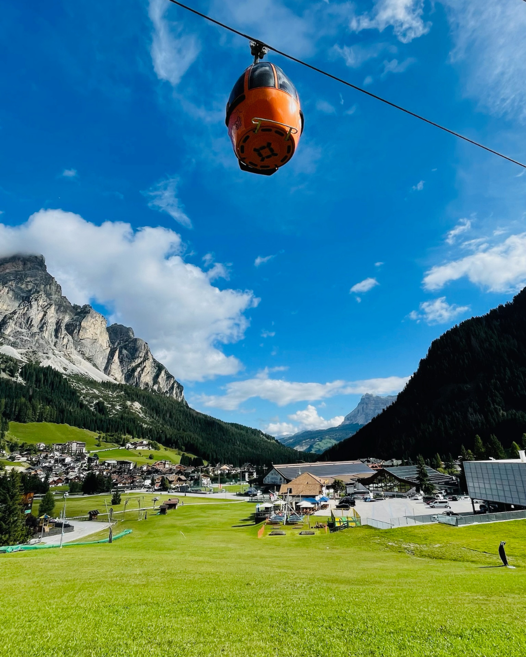 Cable car over a Dolomites village with mountains behind it