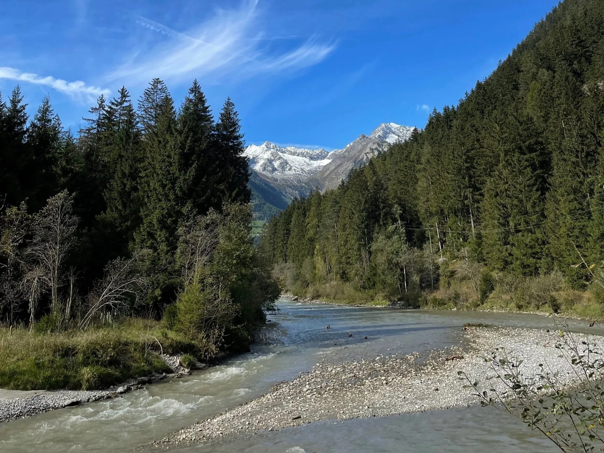 South Tyrol mountain and river with snow in the mountains and lots of trees