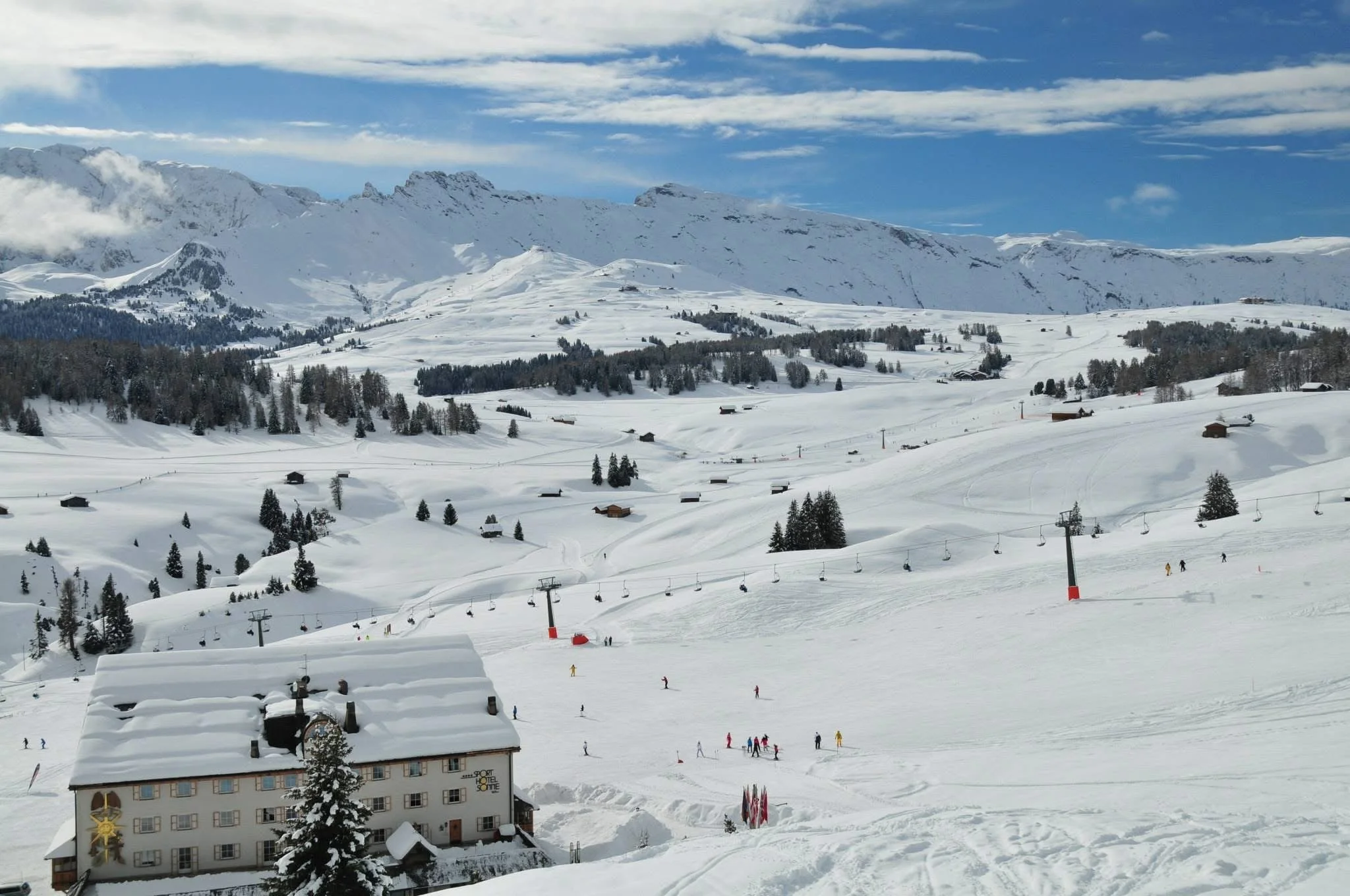 Snowy winter landscape in Val Gardena with ski lifts, mountain huts, and wide open plateau views