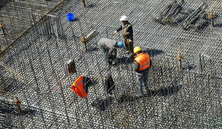 Construction workers reinforcing concrete foundation structure with steel for safe geotechnical design.