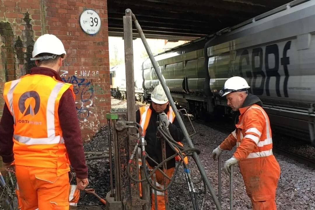 Northpoint Geotechnical engineers operating a drilling rig under a railway bridge as part of a geological and ground investigation.