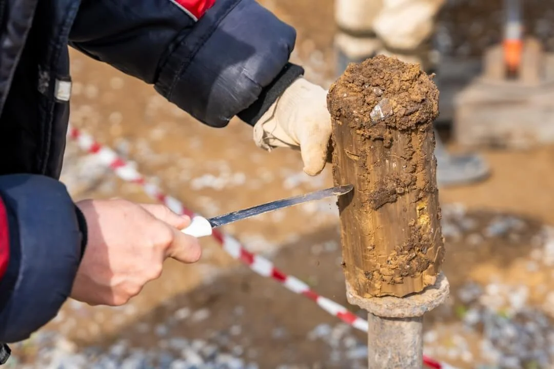 Close-up of soil core sample inspection during Phase 2 intrusive site investigation to assess ground conditions.