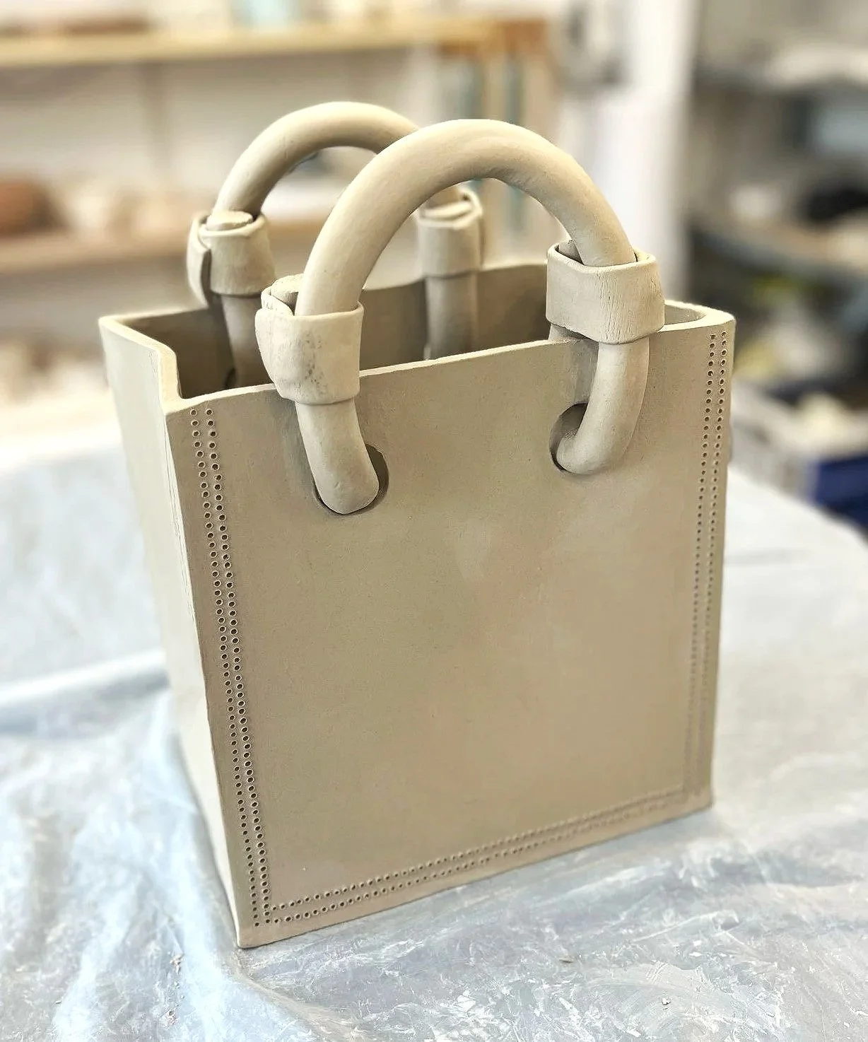 Vase en céramique avant cuisson représentant en sac en cuir avec des anses