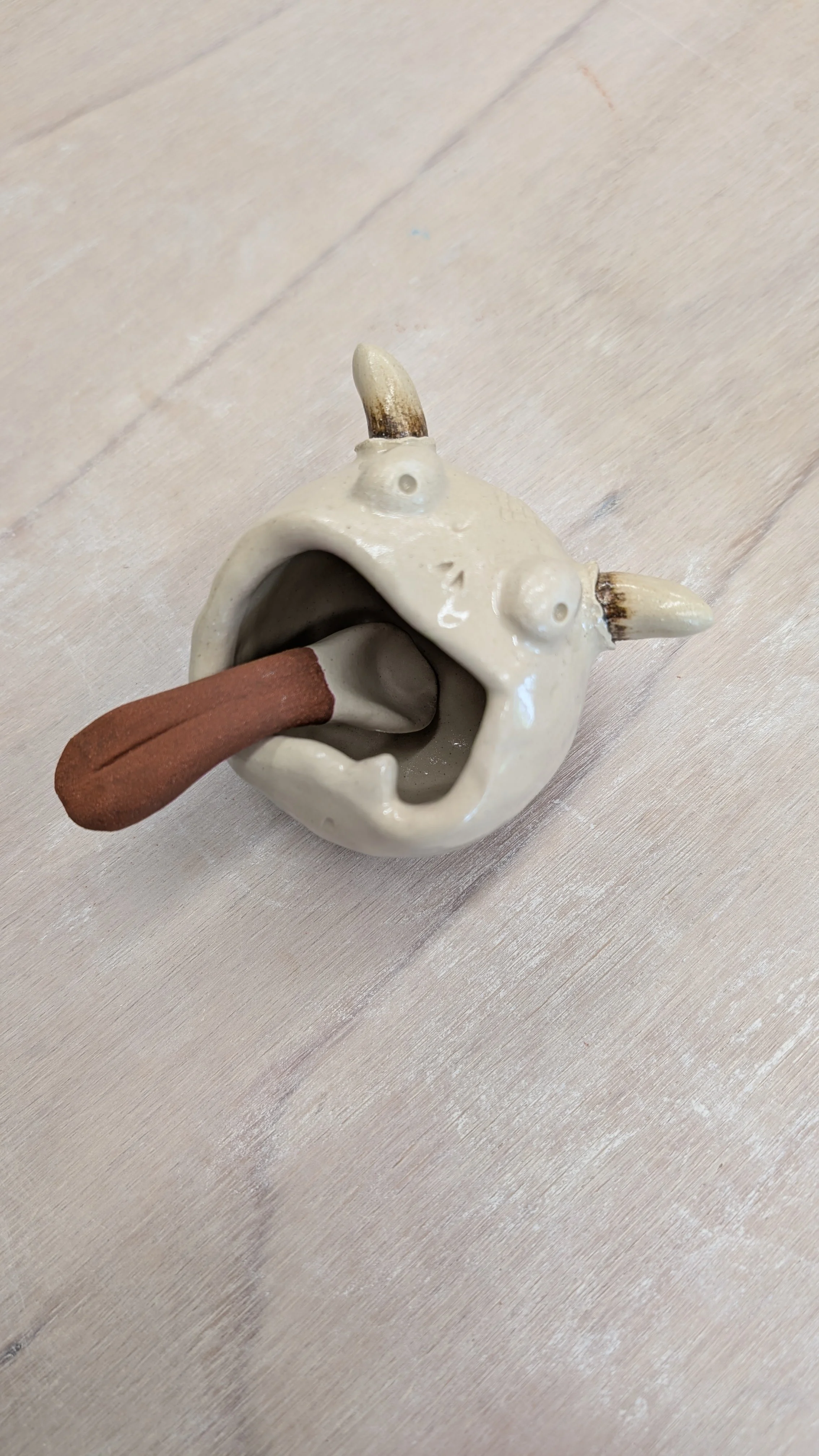 Pot à épices en céramique blanche représentant un petit monstres ayant la bouche grande ouverte et une cuillère rouge en guise de langue