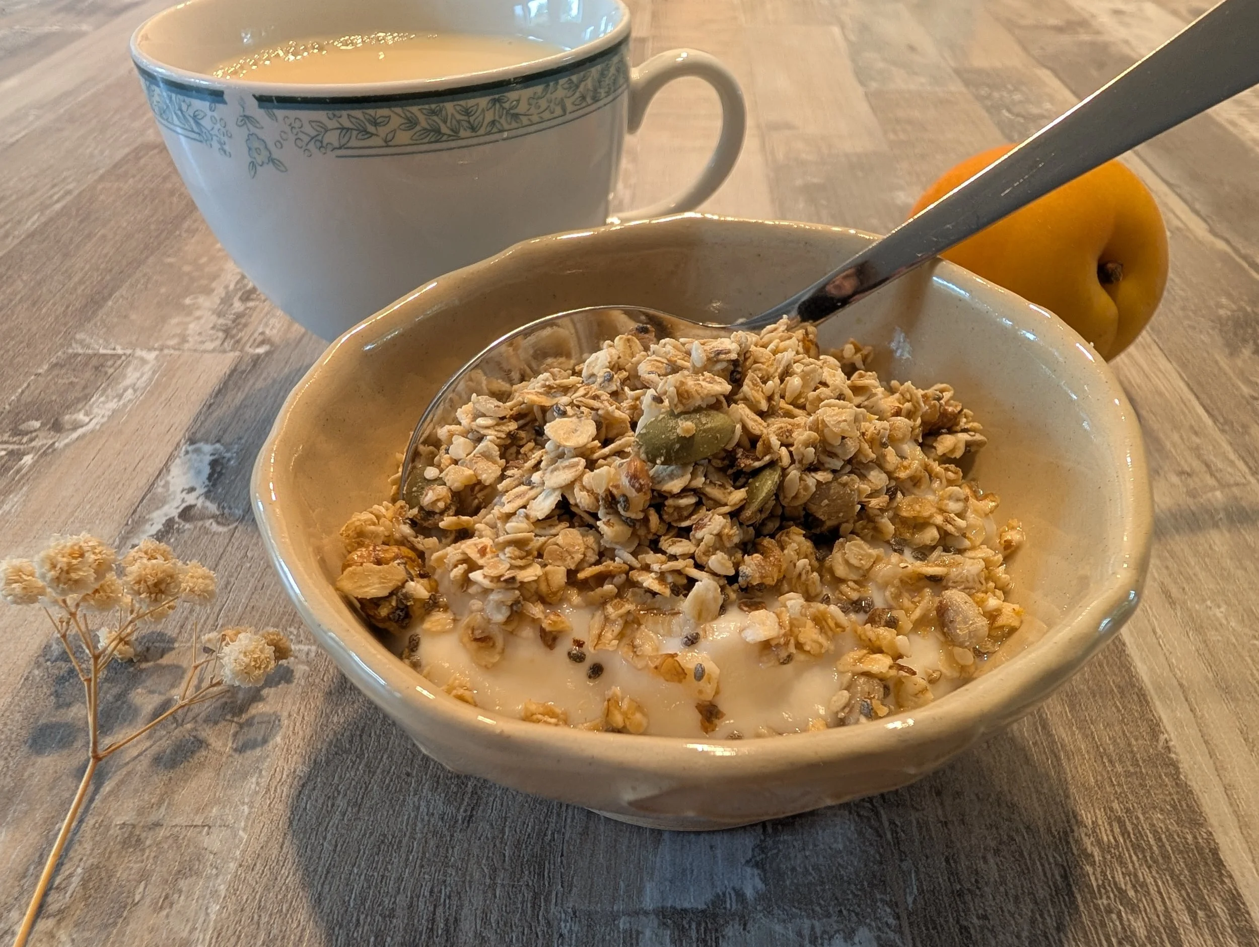Petit déjeuner mettant en évidence un bol en céramique claire contenant du yaourt saupoudré de granola maison