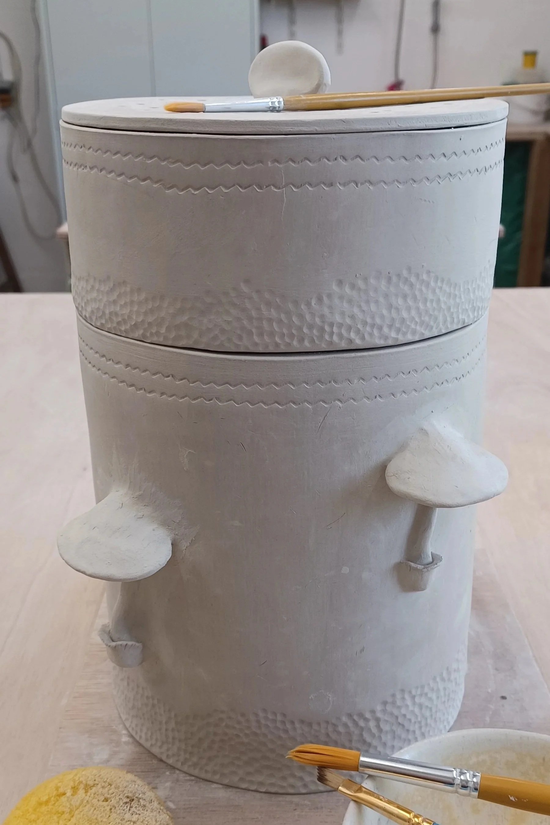 Poubelle de table avec couvercle et décorée de petits champignons, en cours de réalisation en argile et destinée aux déchêts de compost et marc de café.