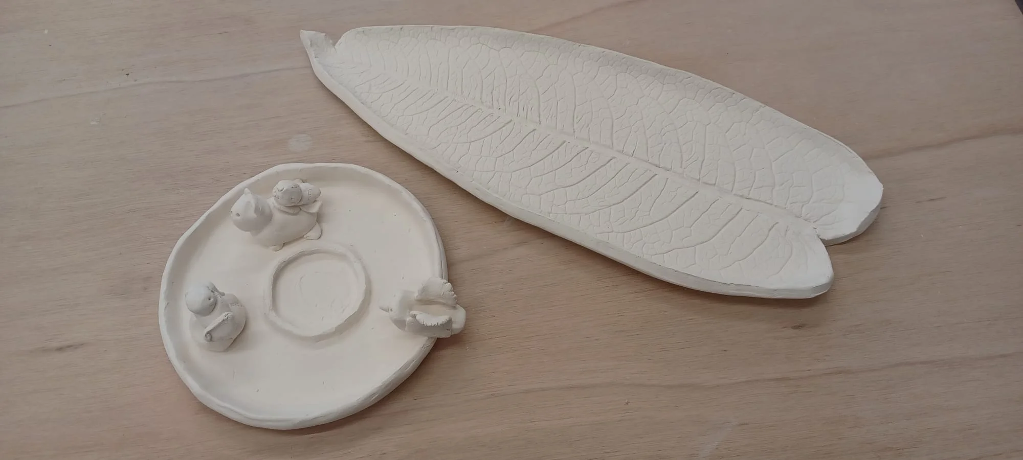 Bougeoir décoré de petites sculptures et plateau-feuille illustrant des créations faites par des adultes et des enfants.
