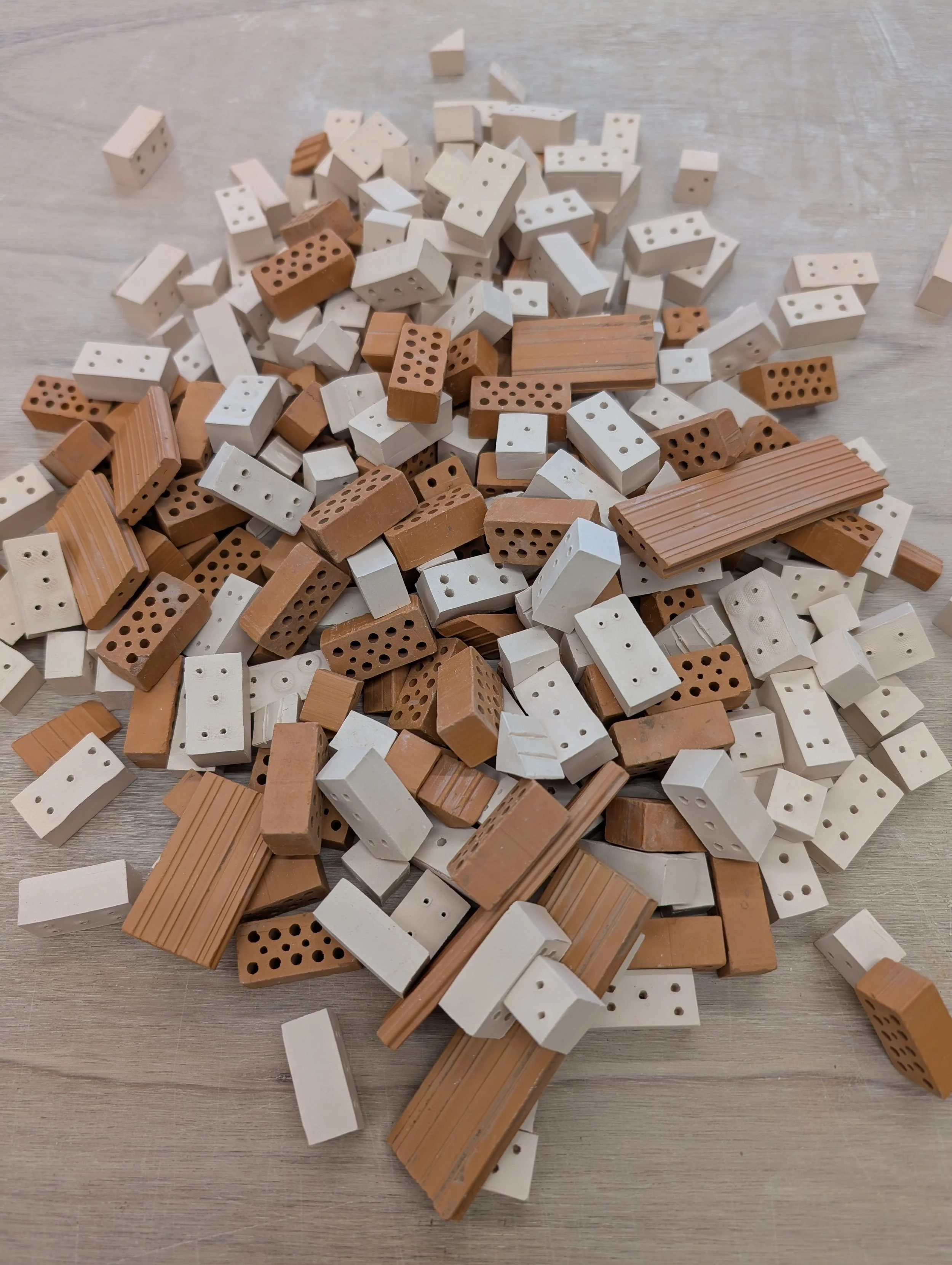 Tas de minis briques réalisées en céramiques blanches et rouges et destinées à jouer ou à construire des maquettes