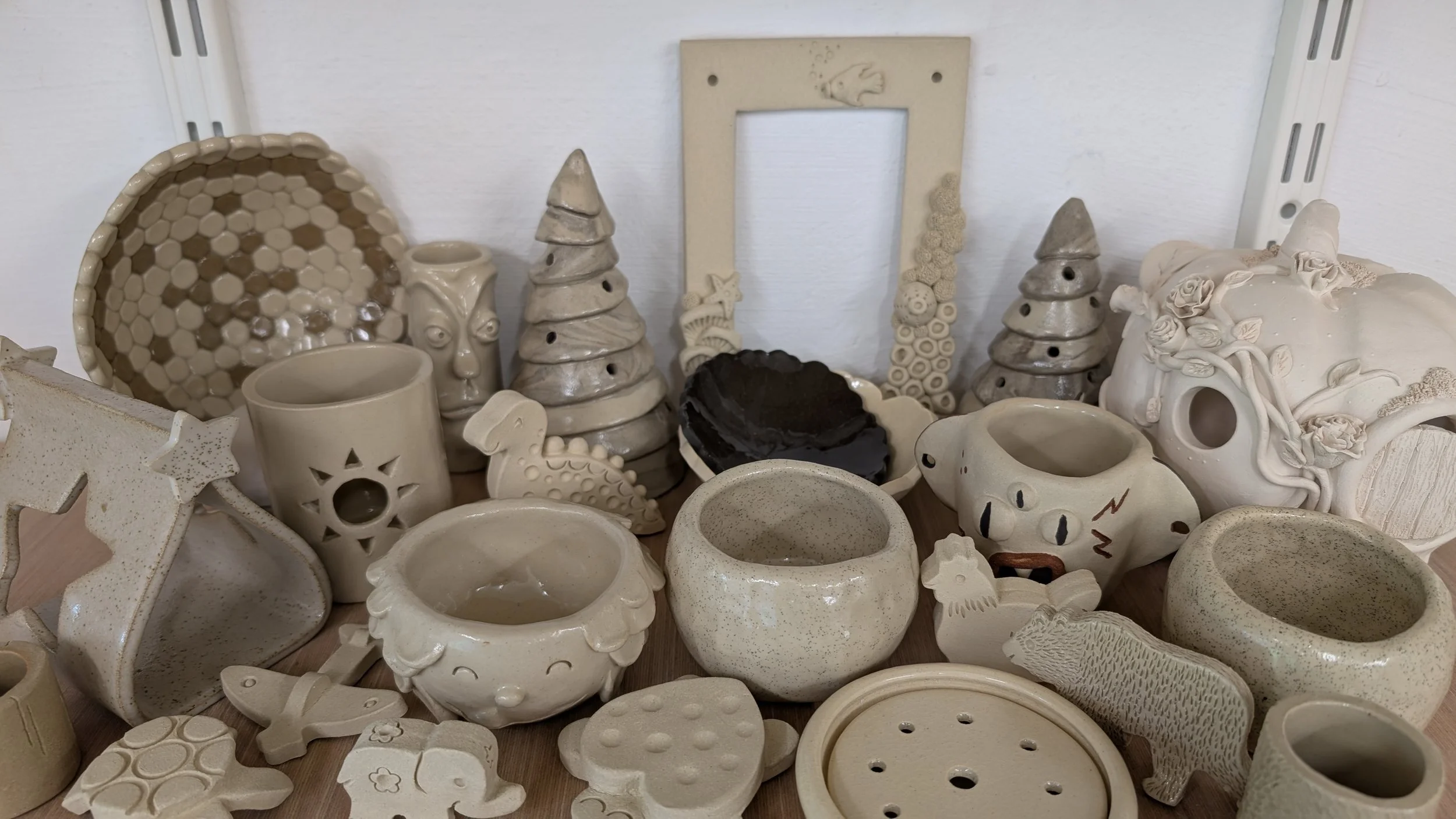 Ensemble de réalisations en céramiques blanches et brunes : coupelle, cadre photo, photophores en forme de sapin, bols, petits animaux, porte-savon, maison de fée en forme de potiron,...