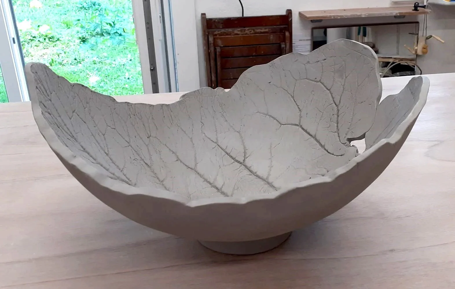 Grand bol à fruits en céramique grise avec empreinte de feuille marquée sur l'intérieur.