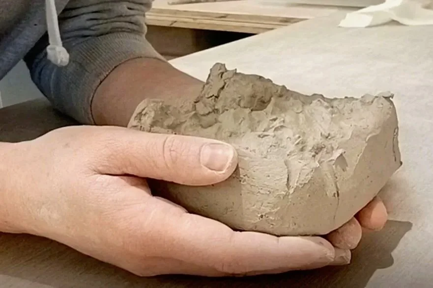 Morceau de pâte d'argile tenu par deux mains et prêt à être modelé