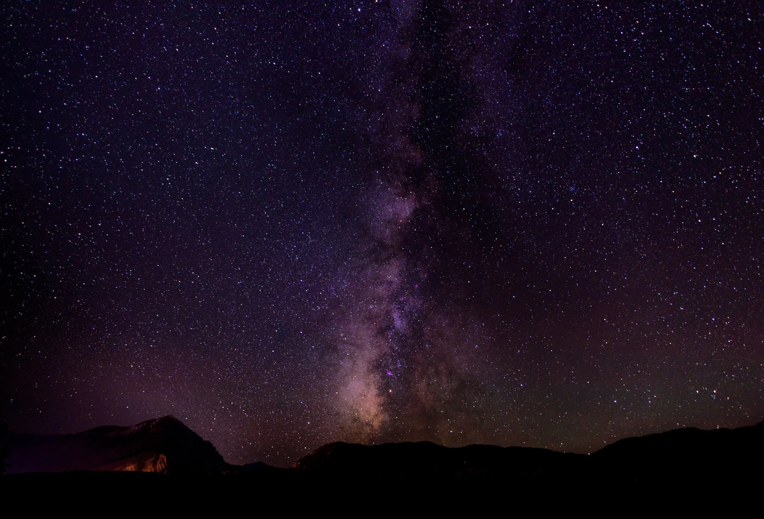 Night sky filled with stars and the Milky Way galaxy over dark mountains.