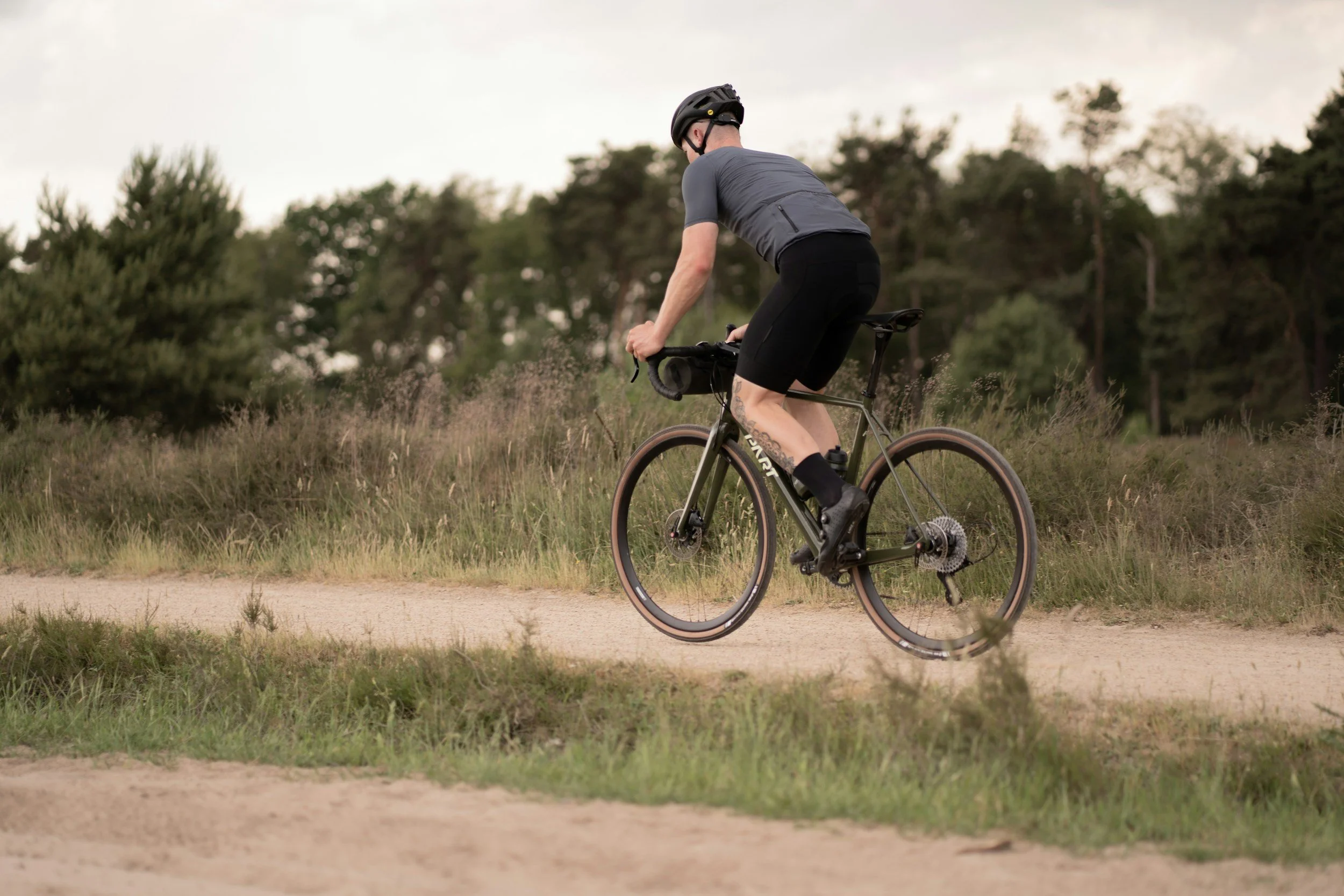 A man riding a mountain bike on a dirt trail in a forested area during daytime.