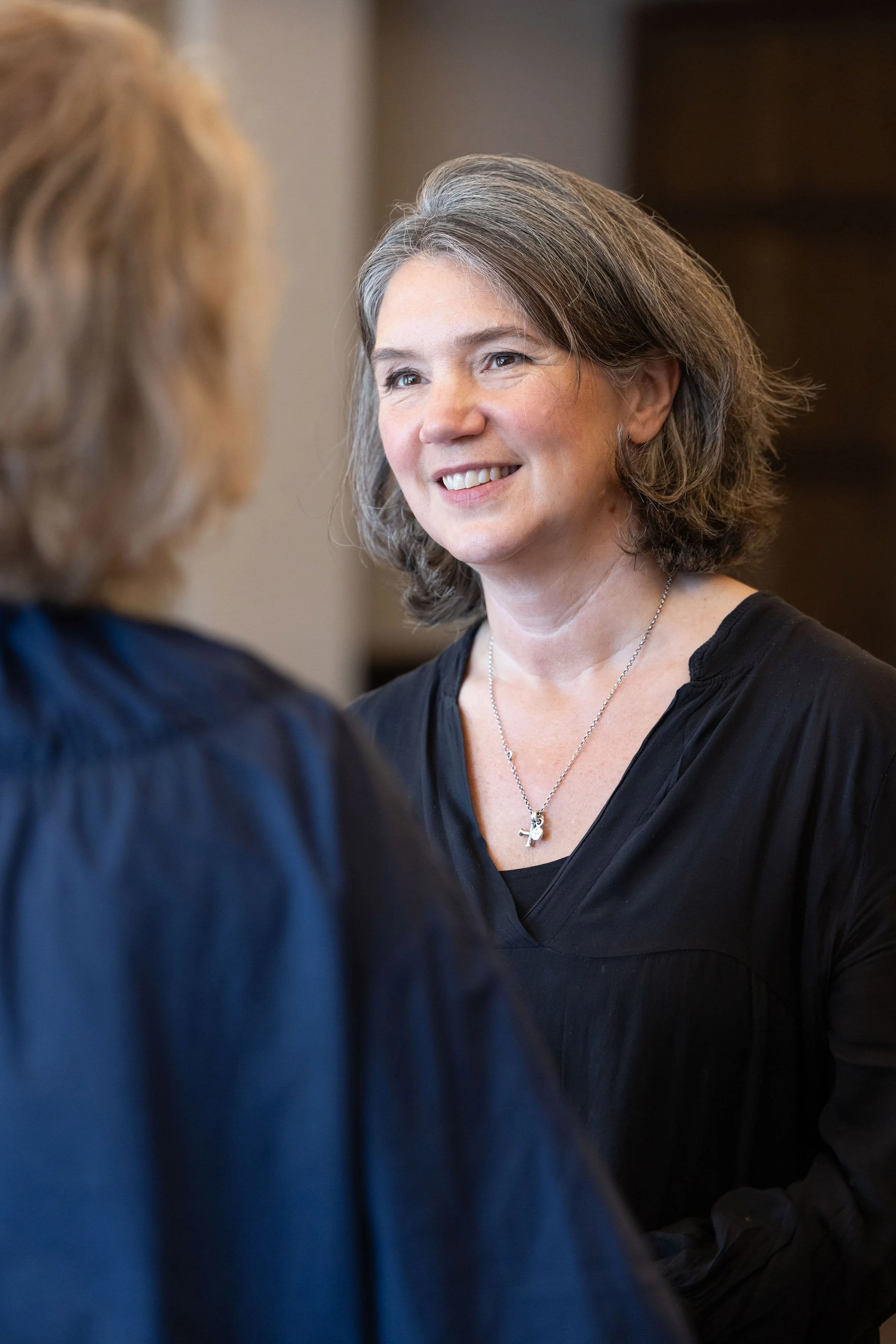 Rebecca Rumsey smiling at a client in a professional setting. Rebecca provides executive coaching, leadership development, team facilitation and coach supervision for individuals and organisations.