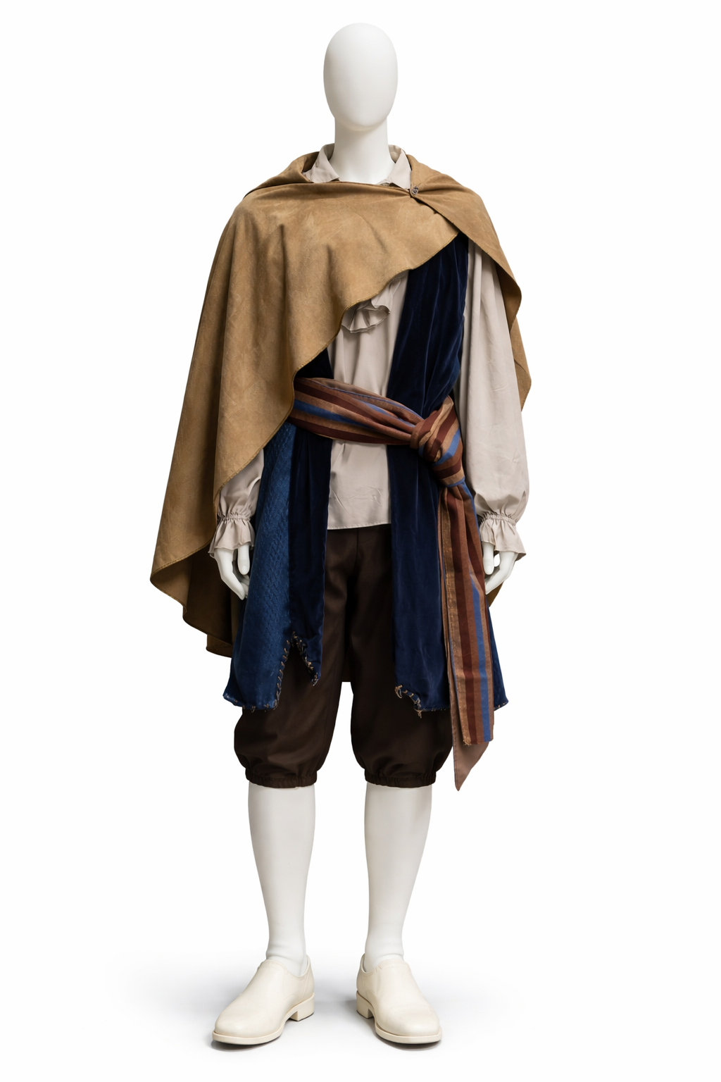 Costume mannequin dressed in historical desert or explorer attire, featuring a beige shirt, brown pants, a large layered cape with a colorful sash, blue and beige scarves, and white footwear. musical', pantomime character hire.