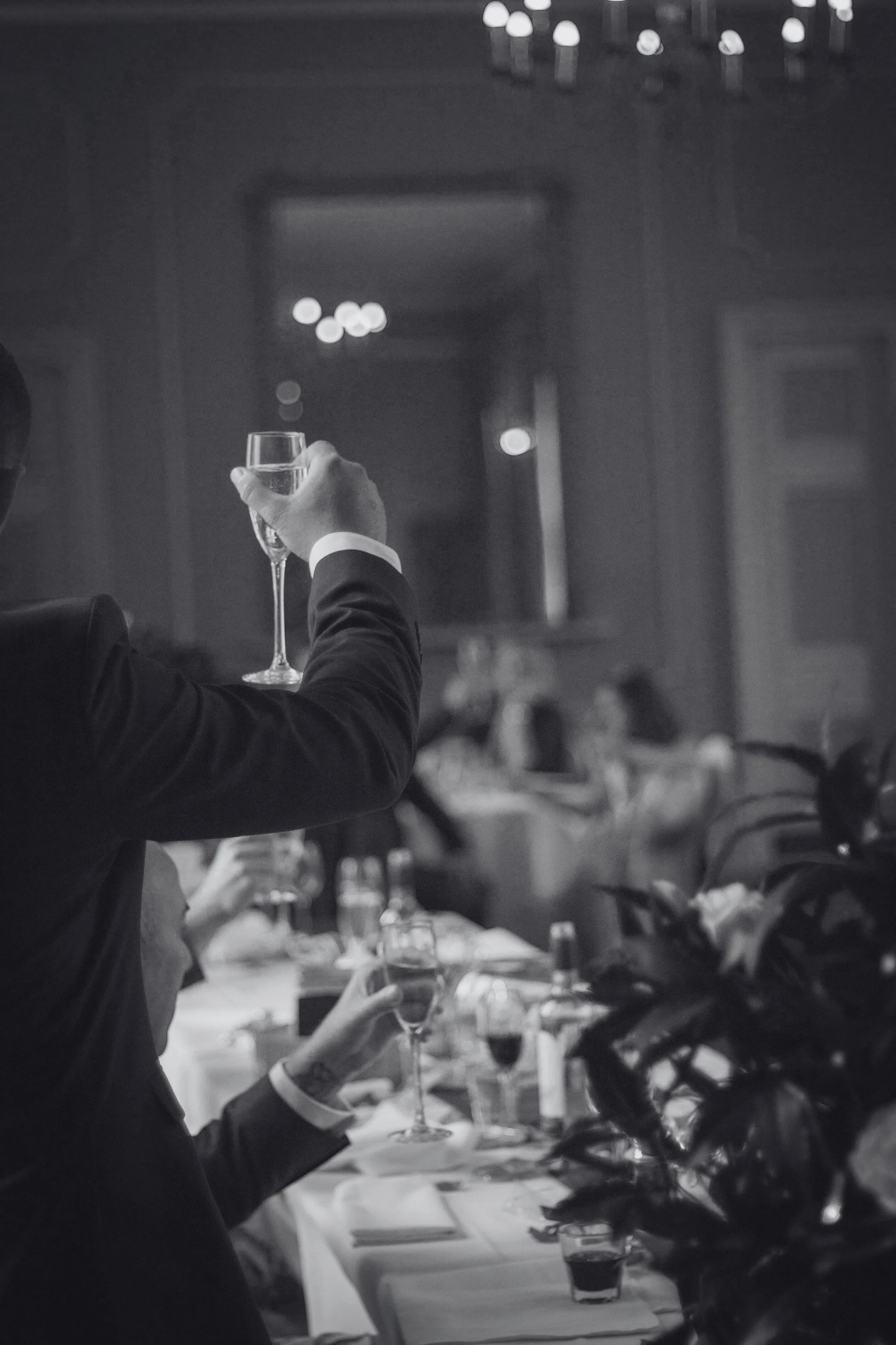 A person in a suit holding a glass of champagne at a formal event or dinner.