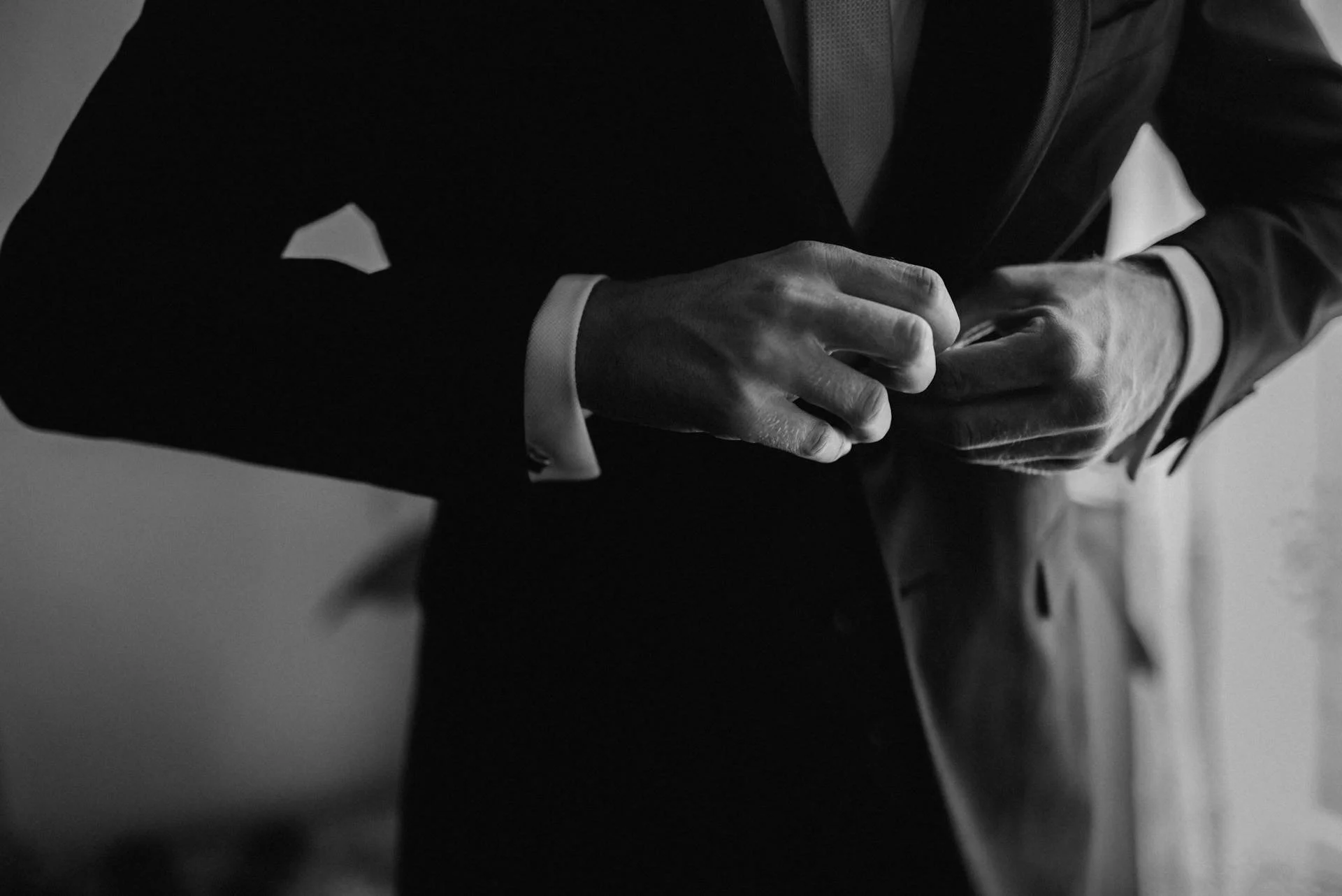 Close-up of a man in a suit adjusting his buttons or cufflinks.