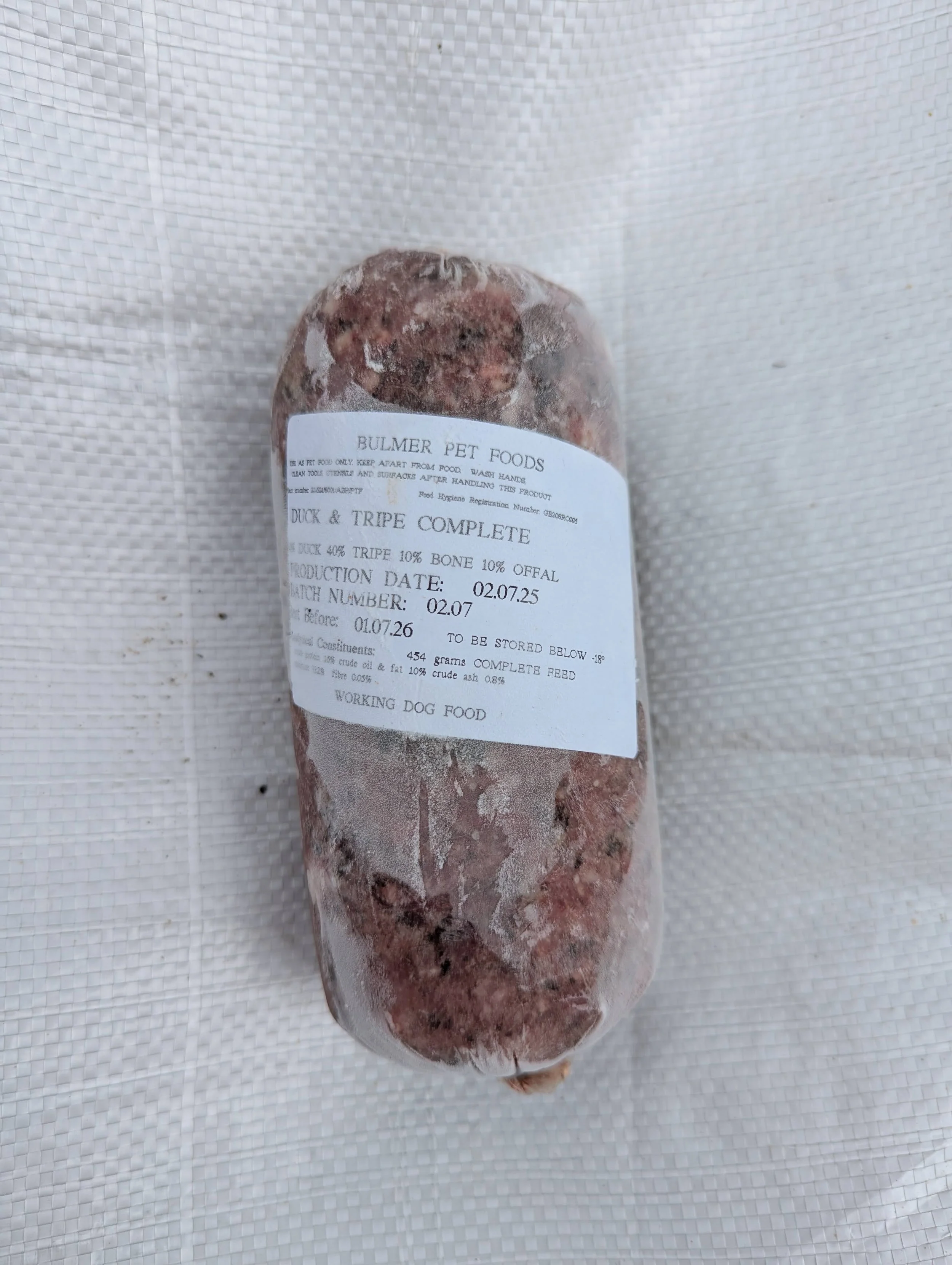Frozen package of raw duck and tripe dog food with a white label that states the brand "Bulmer Pet Foods," product details, and expiration date.