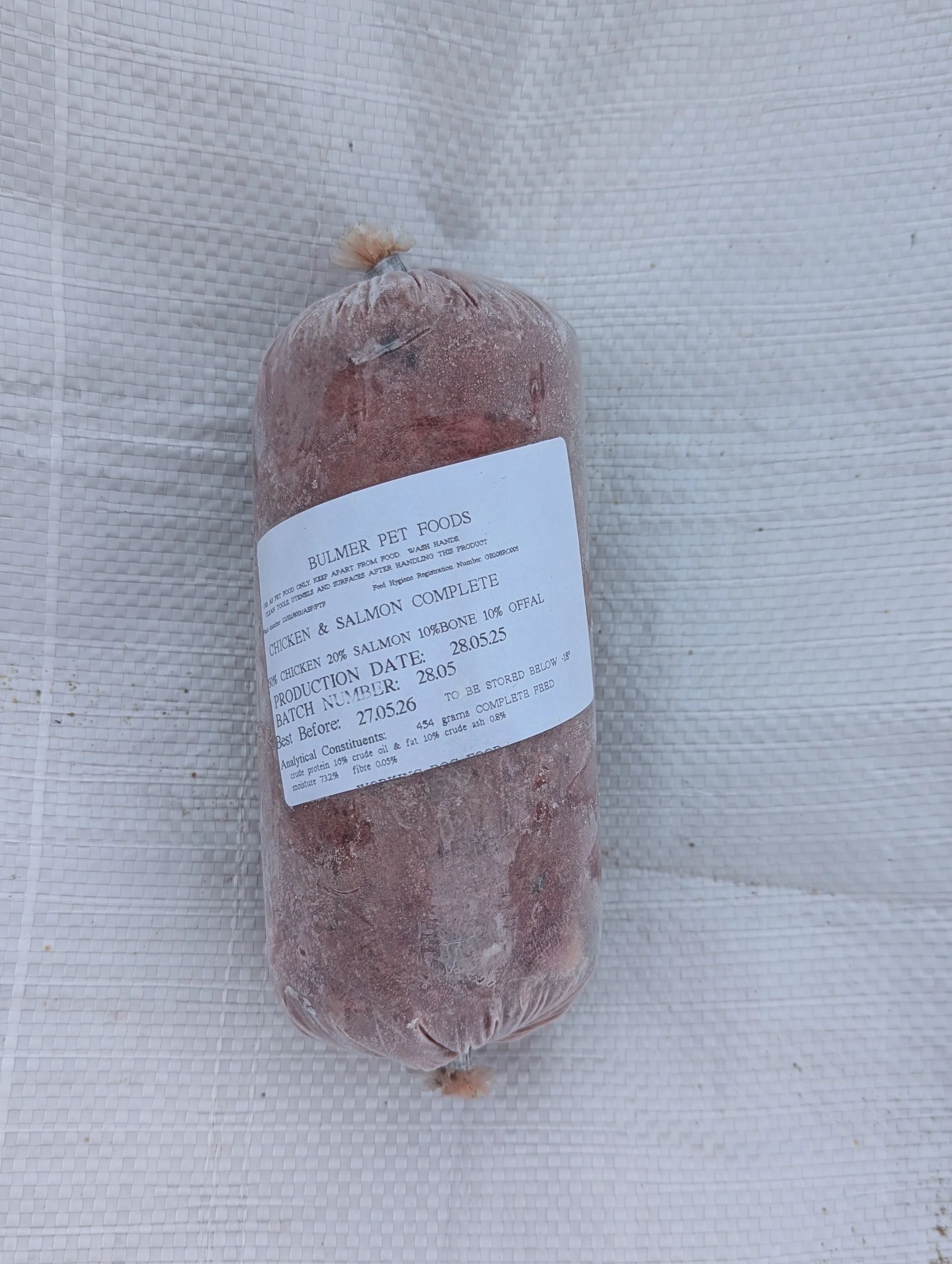 Frozen processed meat product with a label indicating chicken, salmon, and bones, produced in May 2022, from Pullmer Pet Foods.
