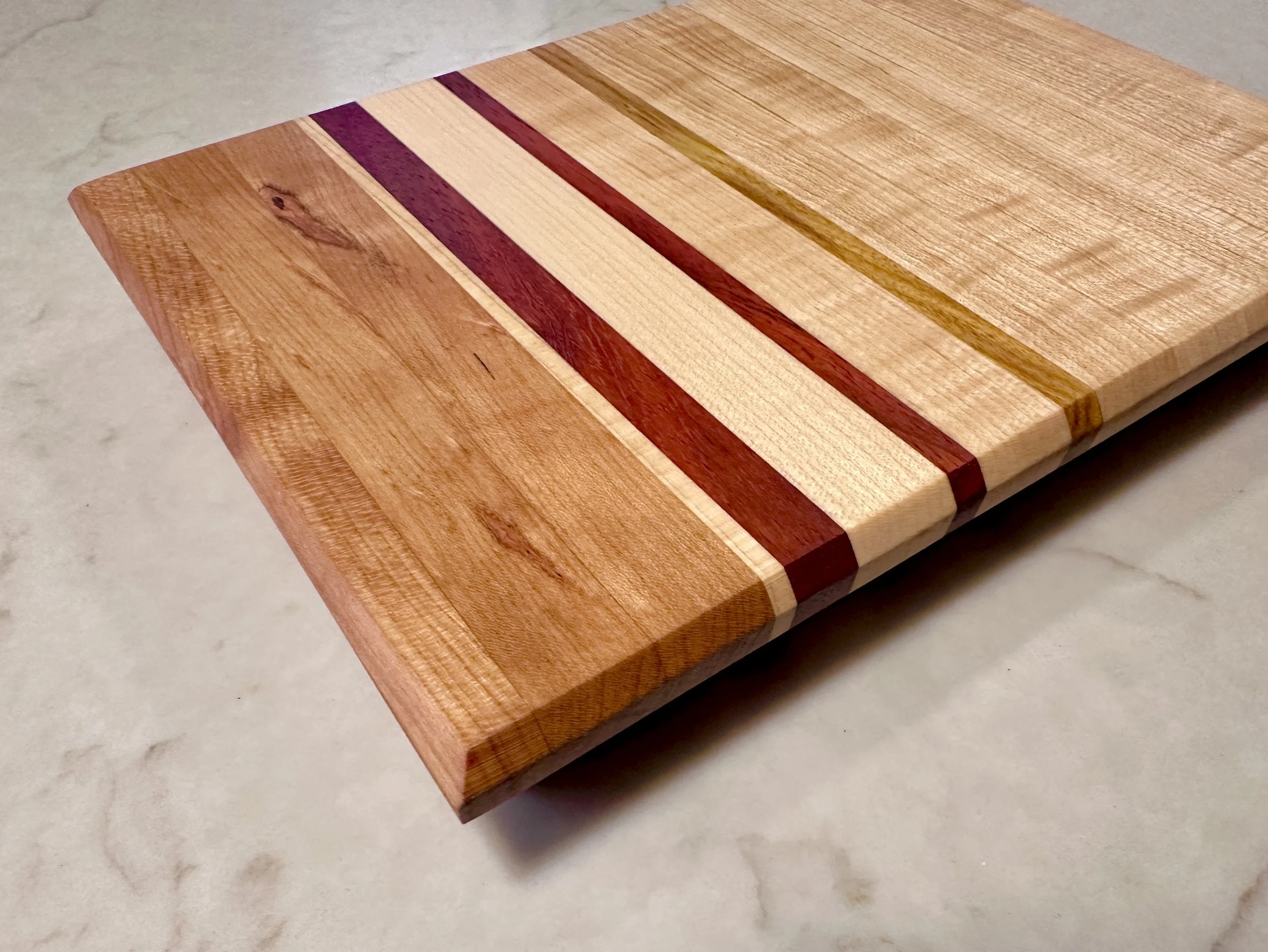 Edge grain cutting board crafted from Cherry, Maple, Padauk and Zebra Wood.