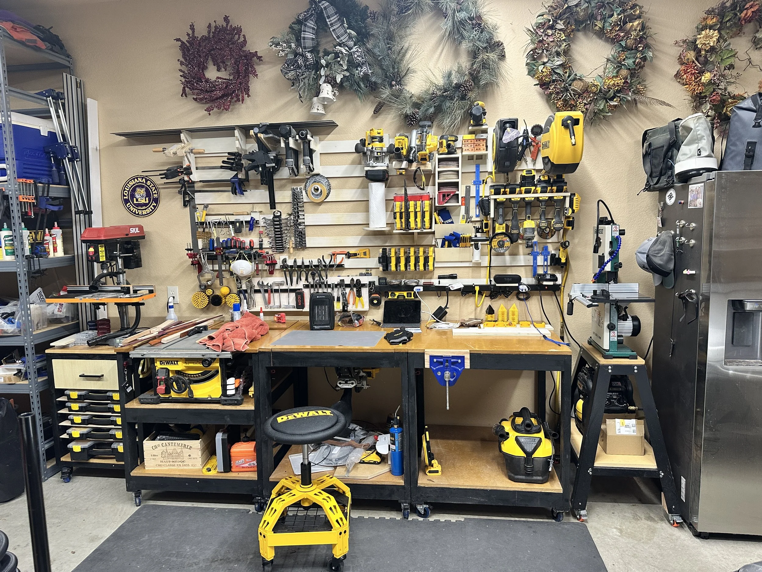 Well-organized workshop wall with tools hanging on French Cleats, workbenches, and Dewalt power tools.