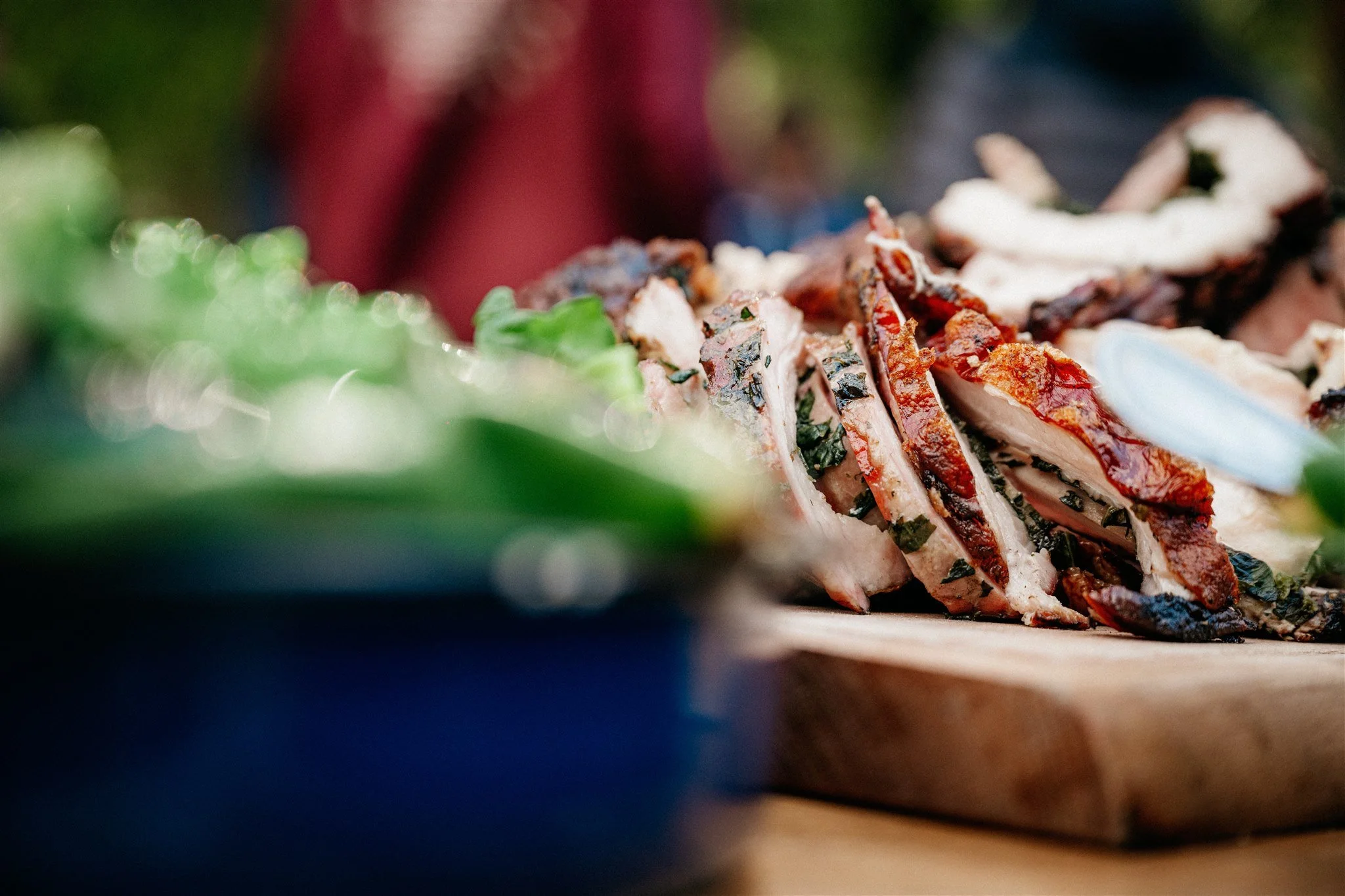 Close-up of sliced grilled chicken with herbs and spices, garnished with chopped vegetables on a plate.