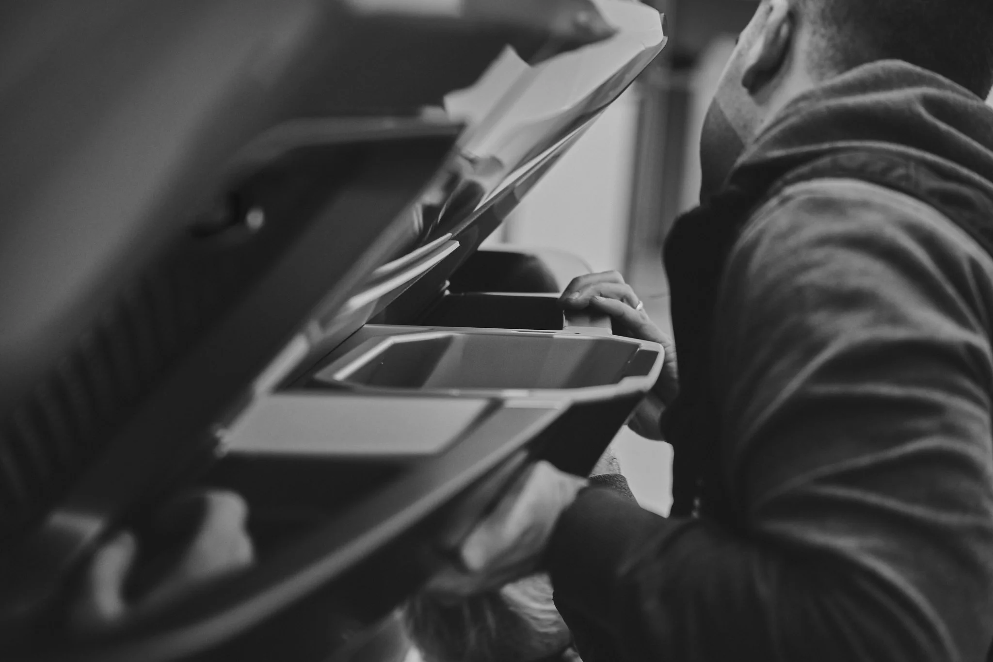 A person using an ATM, leaning forward and pressing buttons on the machine.