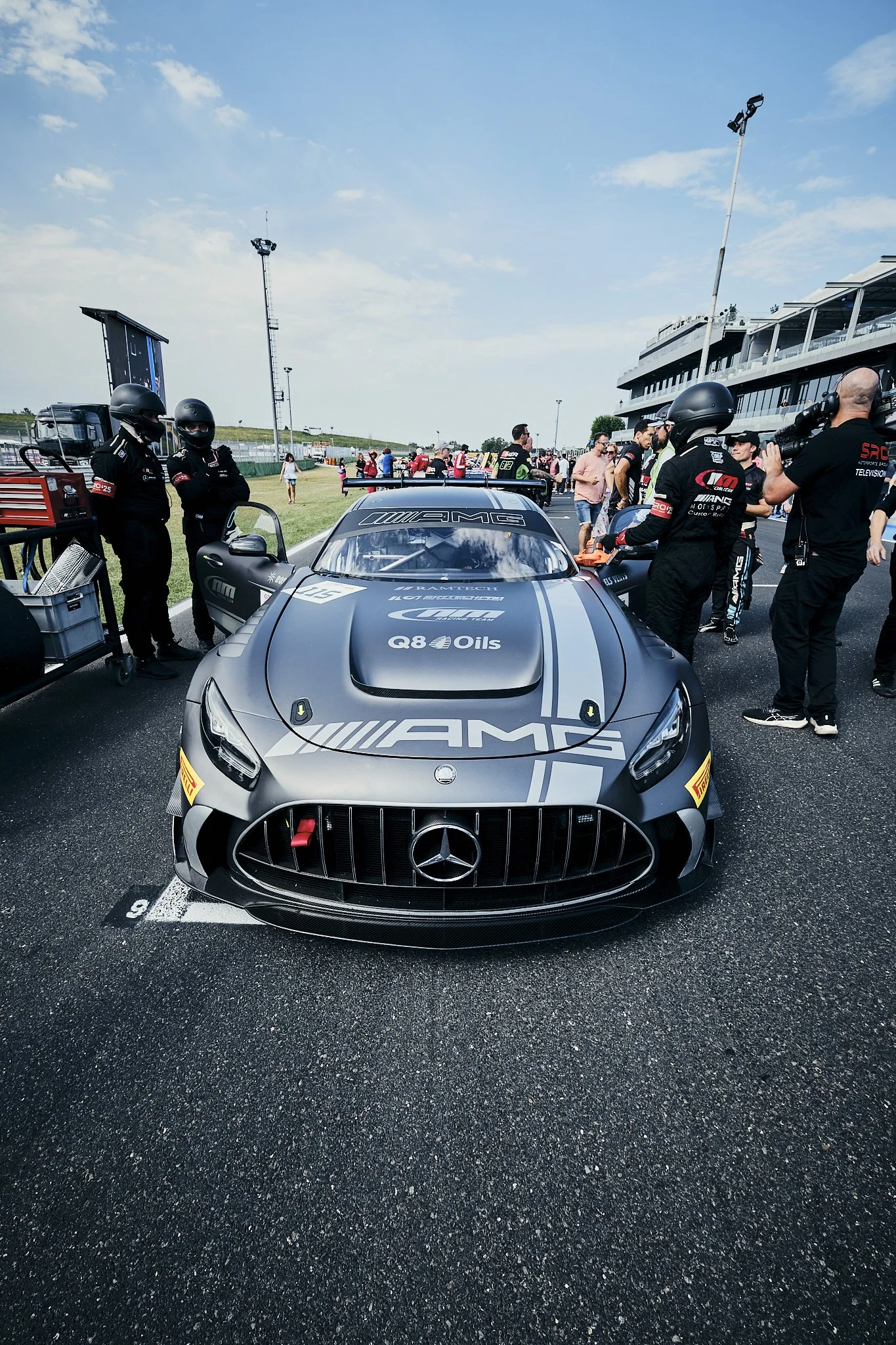 Mercedes-Benz Mercedes-AMG race car in the pit lane with team members and crew around it, at a race track.