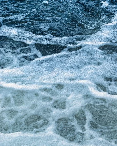 Close-up of ocean water with white foam and waves.