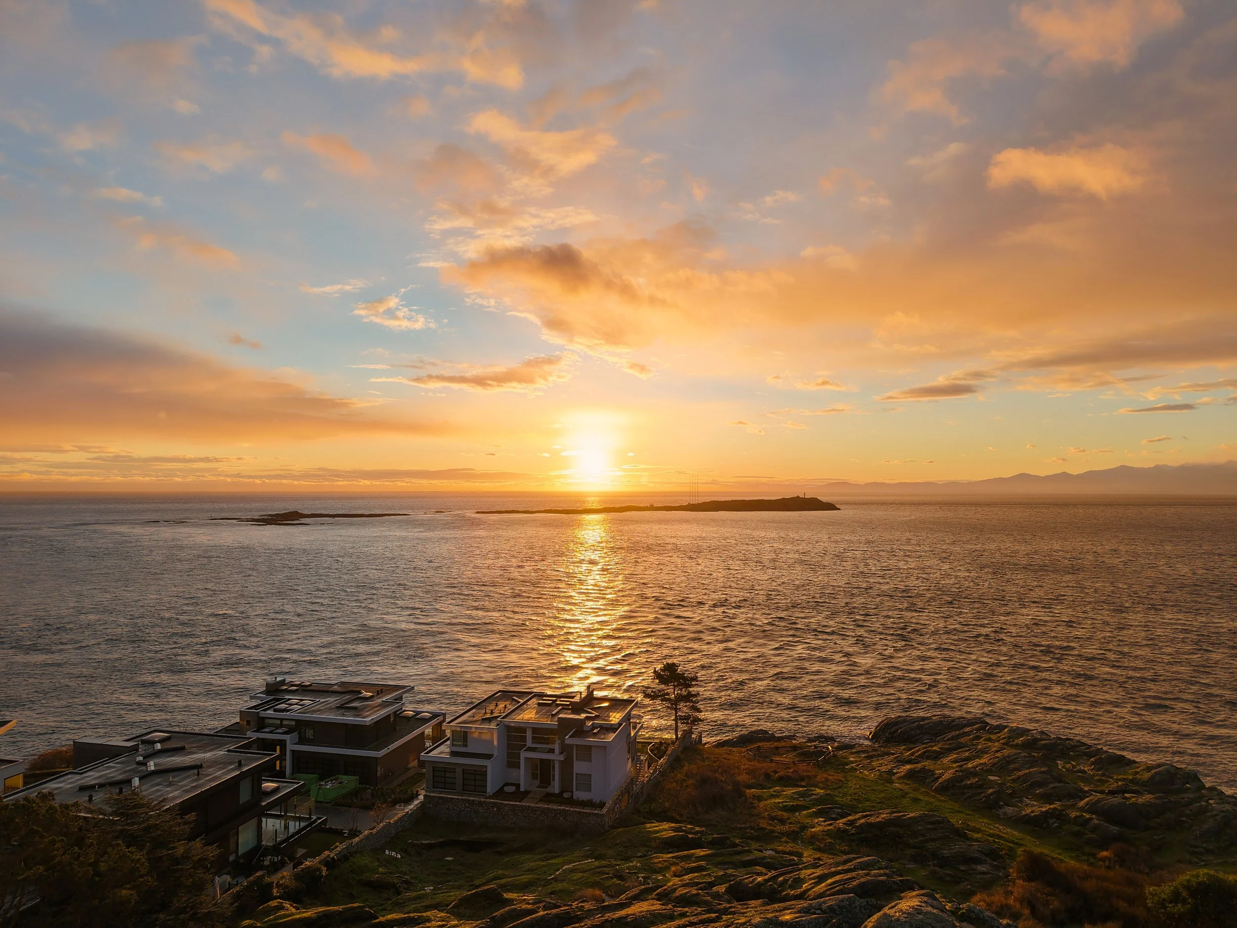 Aerial view from King George Terrace looking toward Trial Island and its lighthouse at sunrise, with soft winter light reflecting across the water off Victoria’s southern shoreline.
