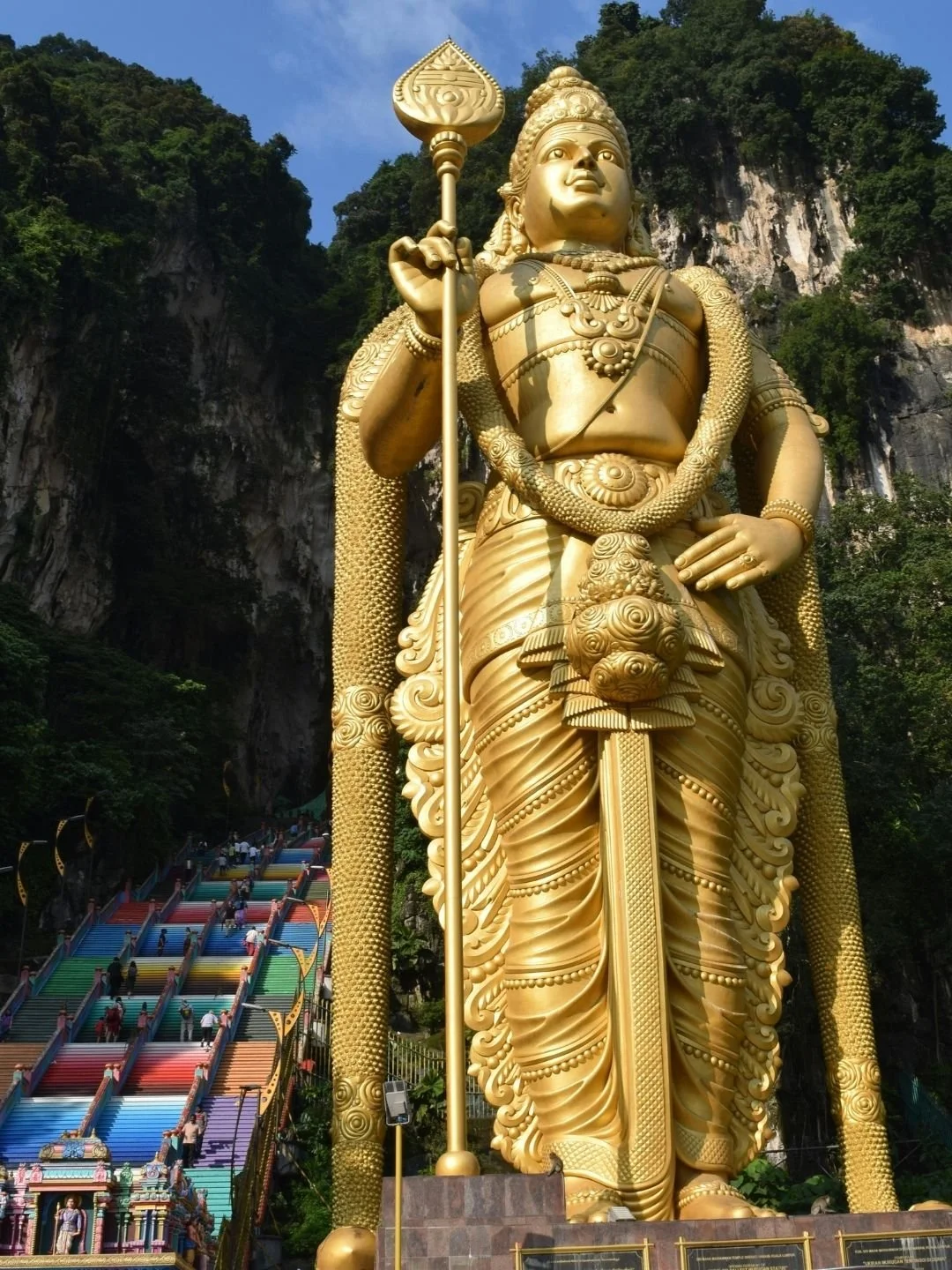 The towering golden Lord Murugan statue beside the colorful staircase of Batu Caves near Kuala Lumpur, Malaysia.
