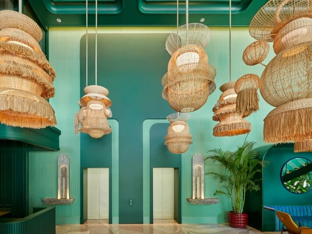 Striking emerald green lobby interior adorned with sculptural woven rattan pendant lighting at The Standard, Bangkok Mahanakhon, Thailand.