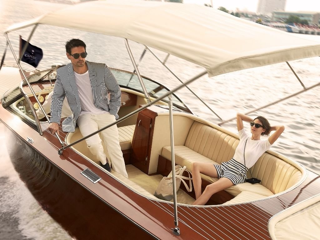Guests cruising the Chao Phraya River aboard Capella Bangkok’s handcrafted luxury wooden river boat in Bangkok, Thailand.