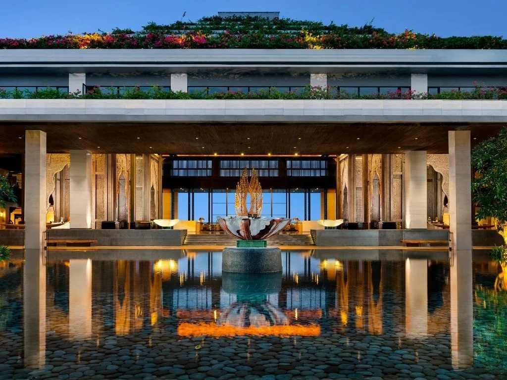 Stately gold sculpture centered in a high-ceilinged lobby with tiered golden architectural lighting – Carpe Asia