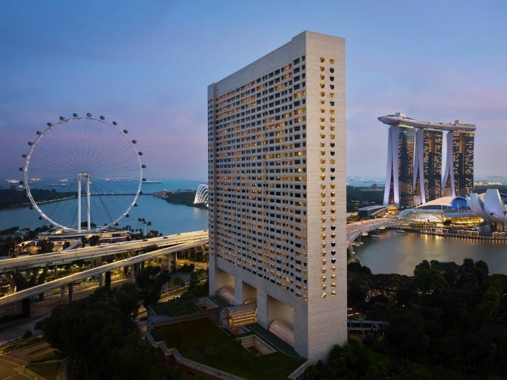 Exterior view of The Ritz-Carlton, Millenia Singapore overlooking Marina Bay, the Singapore Flyer, and the iconic skyline at sunset.