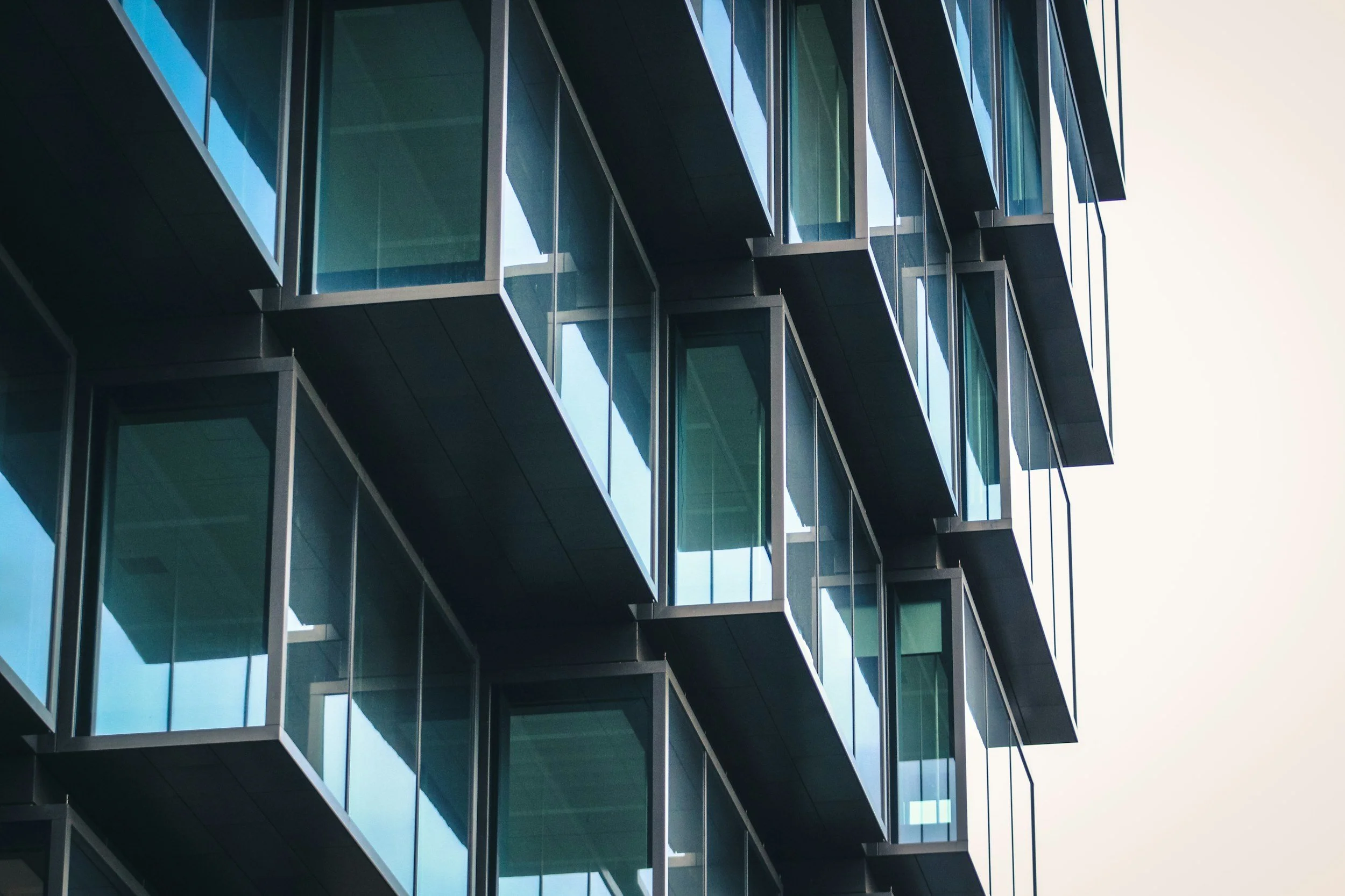 Close-up of modern glass windowed building with reflective windows and dark metal framing.