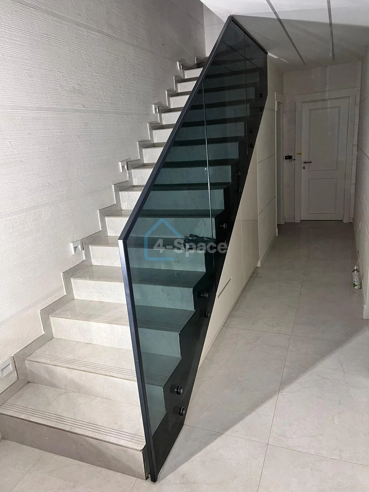 Modern staircase with light-colored steps and a glass railing in a contemporary interior space.
